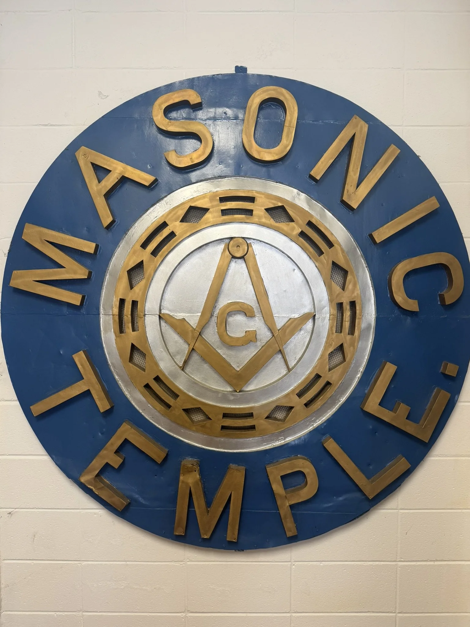 A circular sign with blue and gold colors, featuring the words "Masonic Temple" around the perimeter and a Masonic emblem in the center.