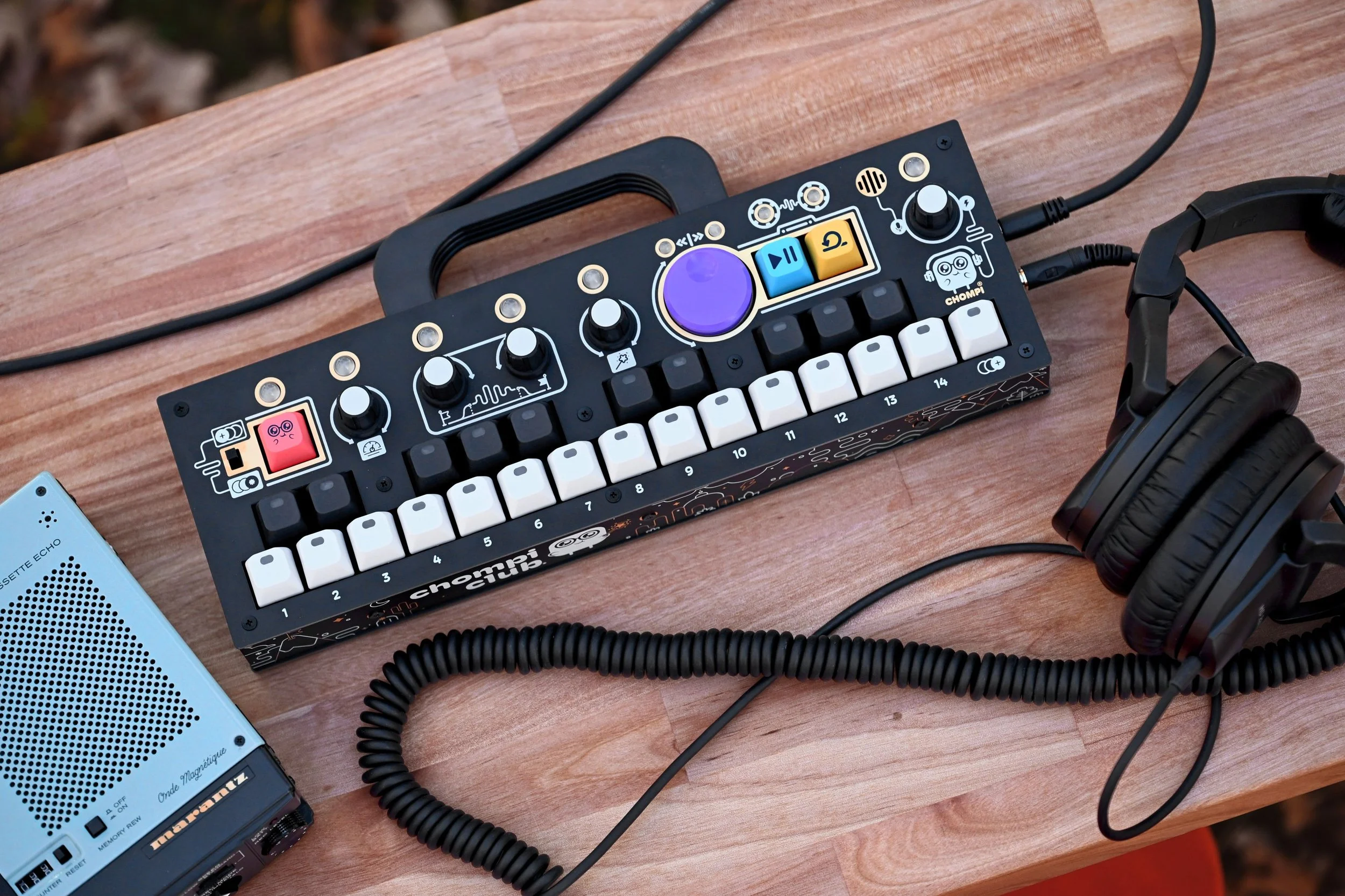 CHOMPI sampler on a wooden table next to a pair of headphones.