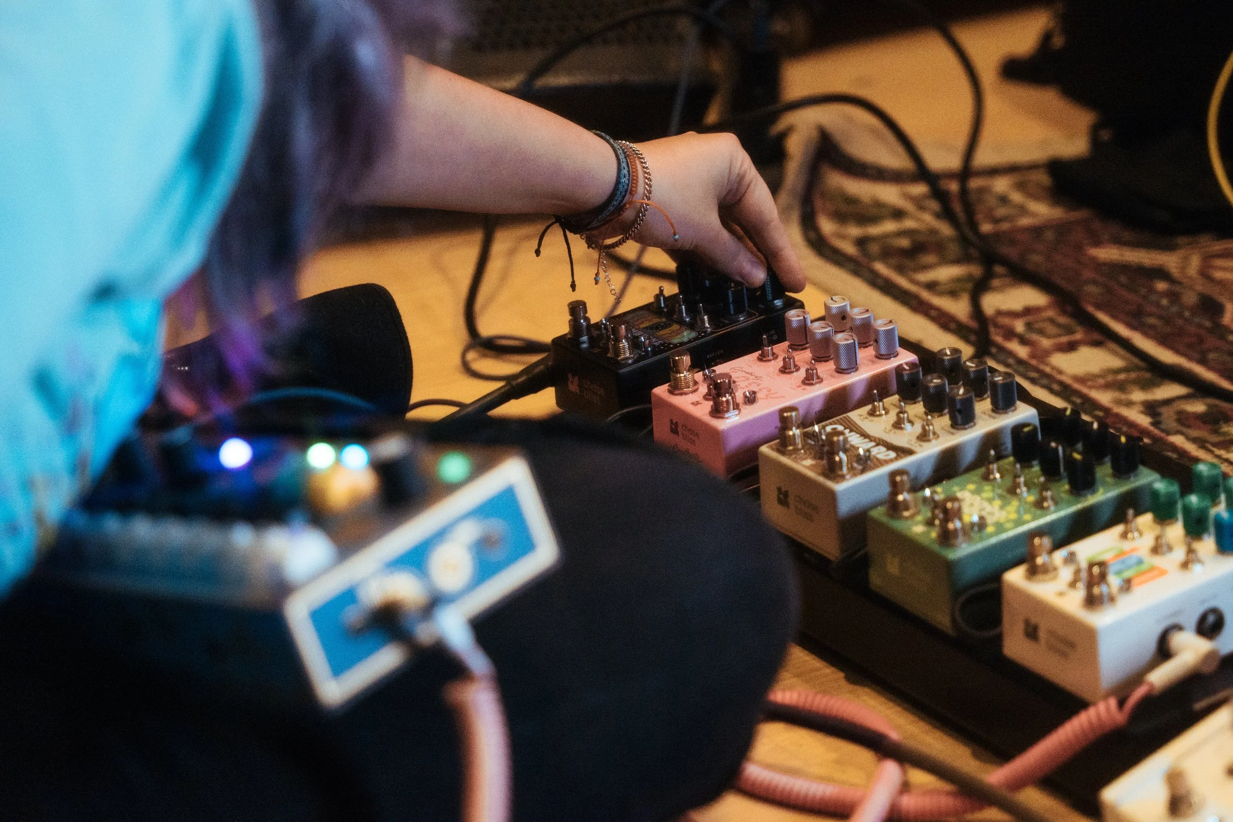 AJ playing CHOMPI with a Chase Bliss pedal board, adjusting settings on Wombtone pedal. AJ tocando o CHOMPI com uma pedaleira Chase Bliss e ajustando as configurações do pedal Wombtone.