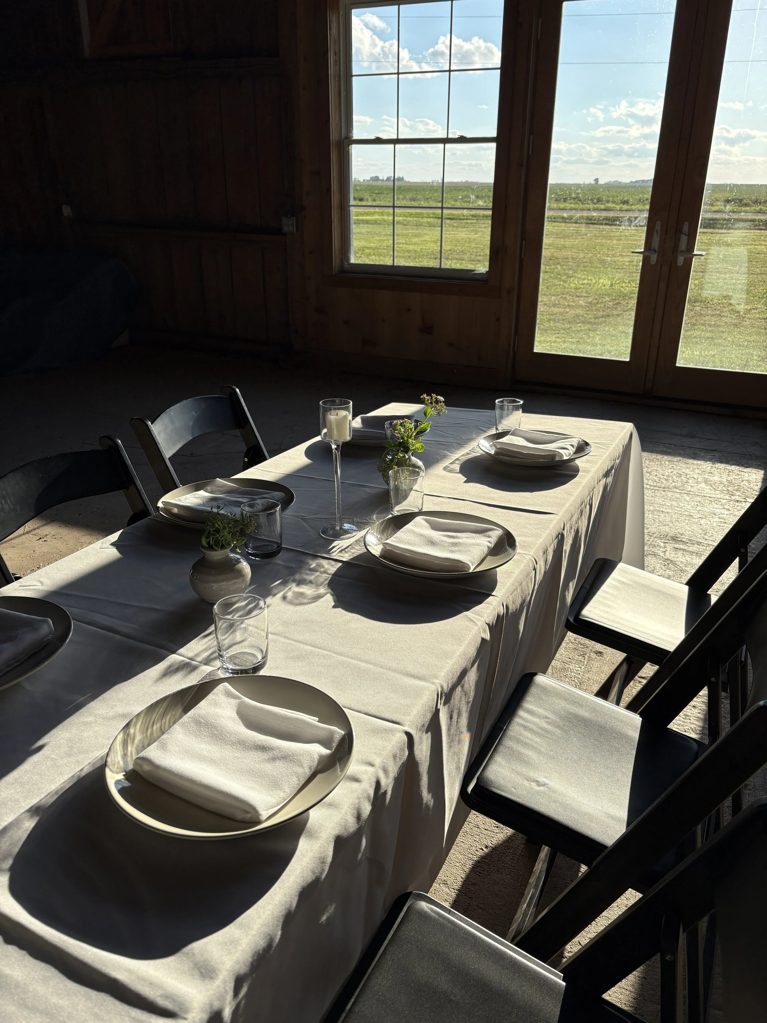 Elegant table set up in Barn, near large west facing windows, sunset