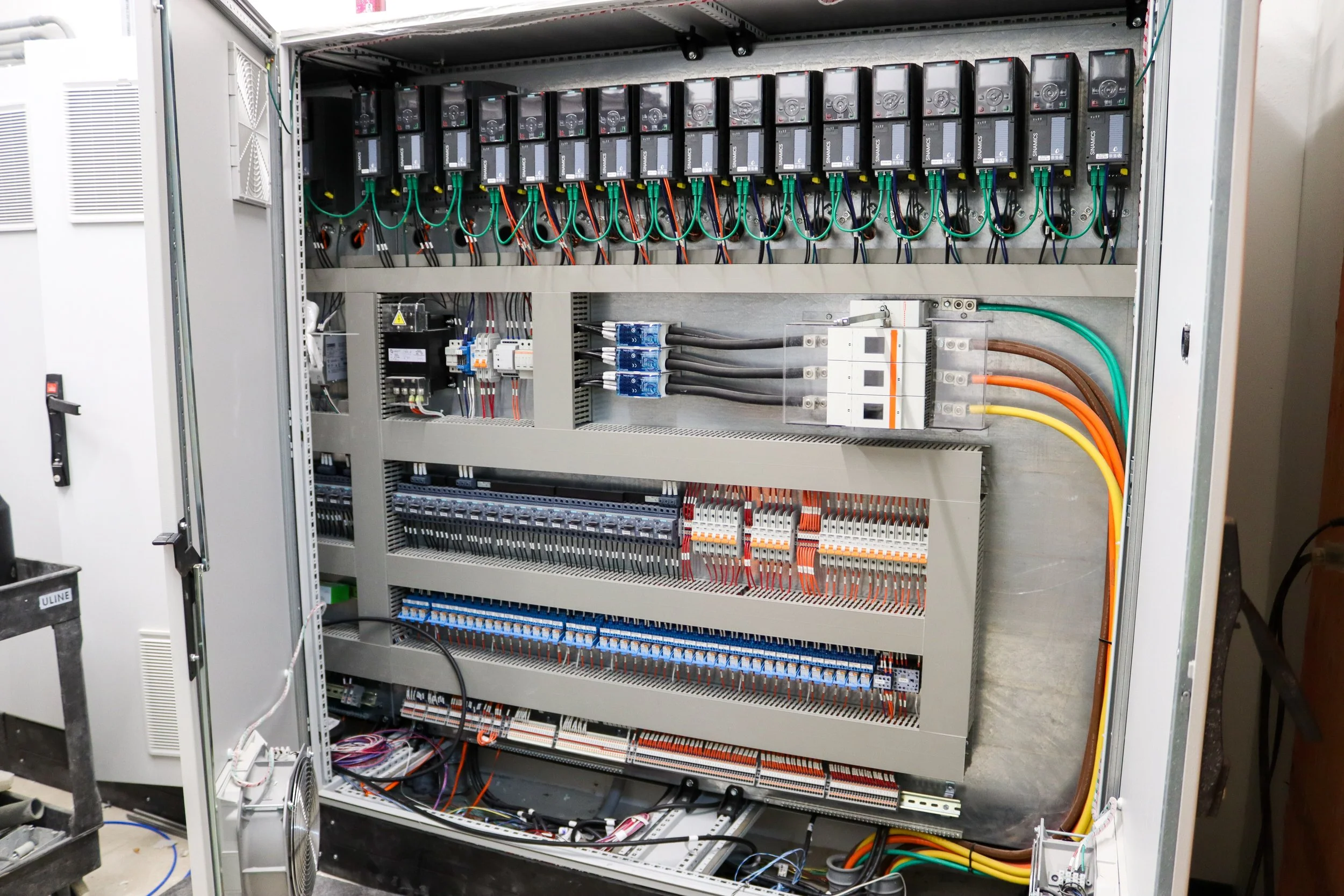 Electrical control panel with multiple circuit breakers, wiring, and terminal blocks.