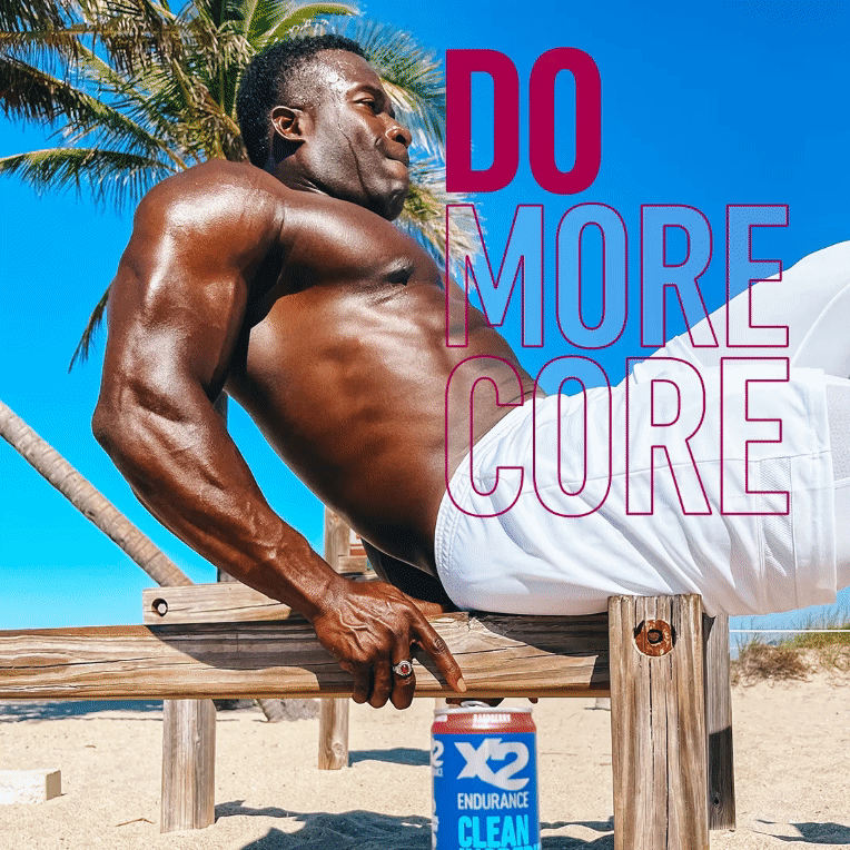 X2 Energy organic social ad for sports drink campaign featuring male fitness influencer doing core workout on outdoor beach equipment with X2 can in frame and headline “Do More Core.”