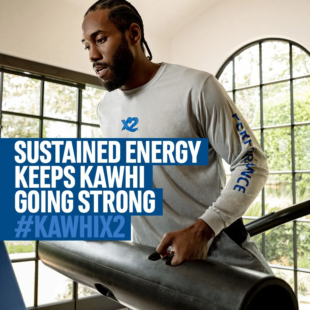 X2 Energy social ad for sports drink activation featuring NBA All-Star Kawhi Leonard training indoors with the message “Sustained energy keeps Kawhi going strong” and hashtag #KawhiX2.