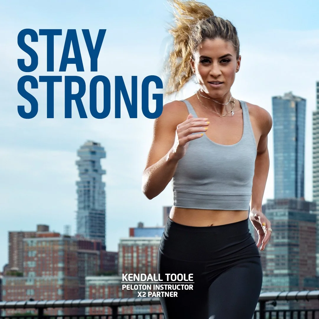 X2 Energy social ad for fitness beverage campaign featuring Peloton instructor Kendall Toole stretching outdoors in New York City with tagline “Stay Strong"