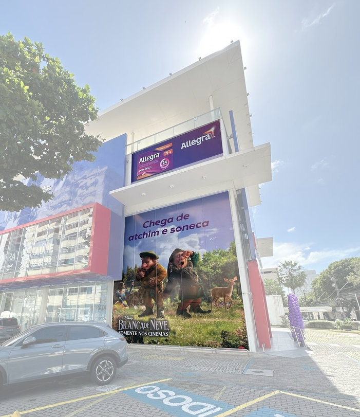 Large Outdoor pharmacy display in Brazil. Signage shows Sneezy and Sleepy with the portuguese headline "Chega de atchim e soneca" (Enough with sneezing and sleepiness") for Allegra partnership with Disney's SNow White.