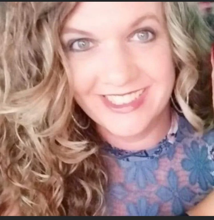 A woman with long, curly hair smiling at the camera.