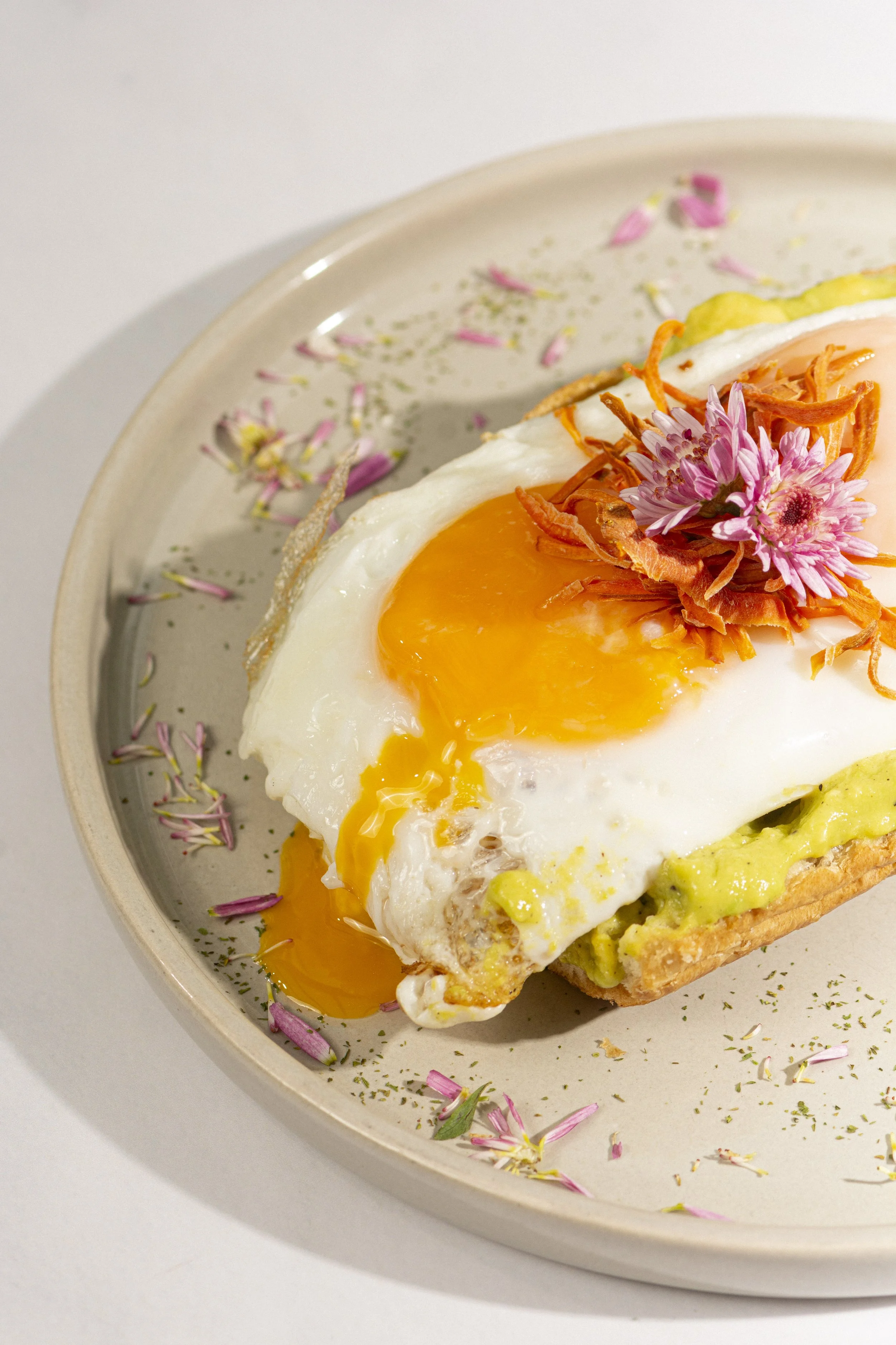 Tostada con aguacate, huevo frito y flores comestibles