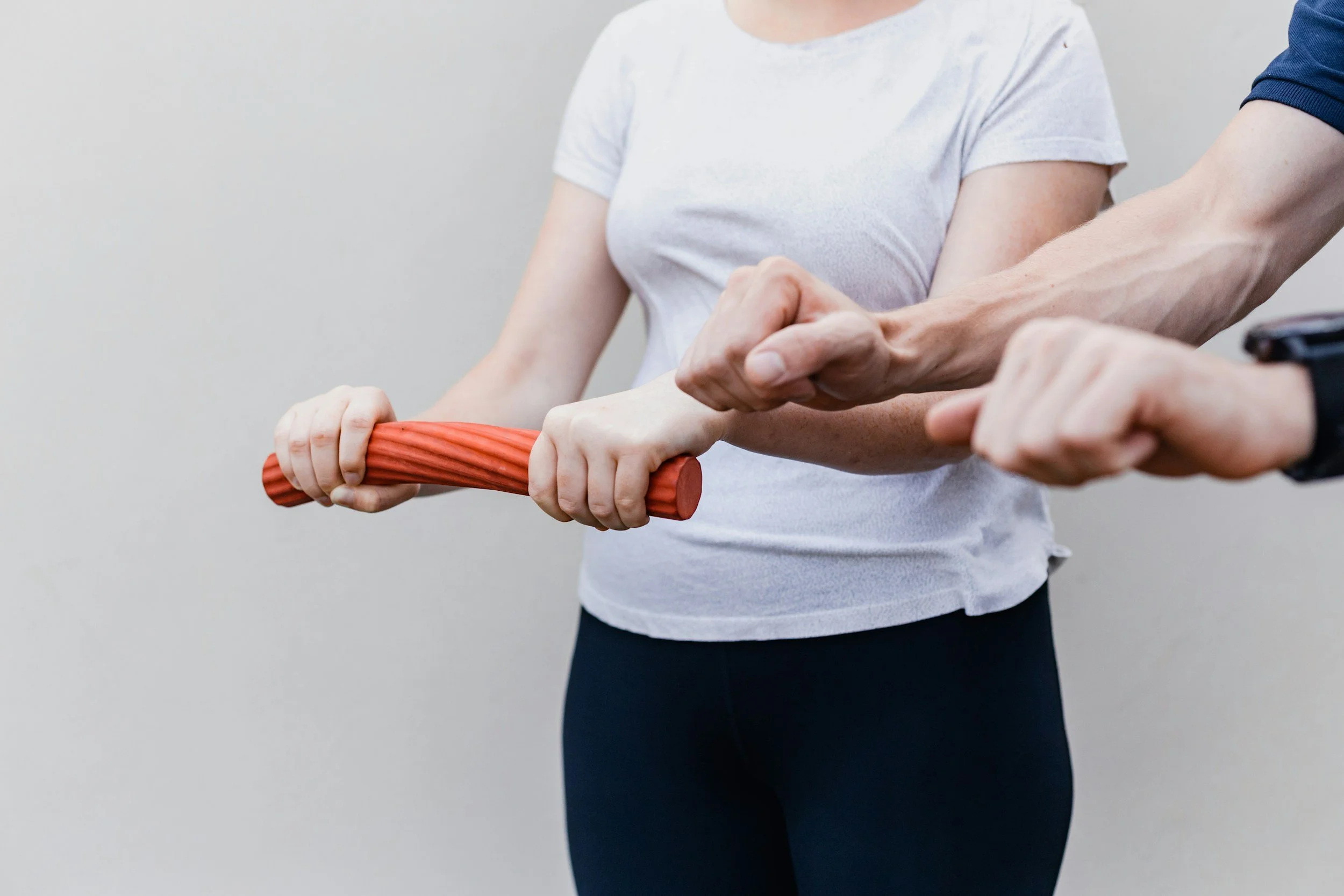 Person holding a massage roller with assistance from another person.