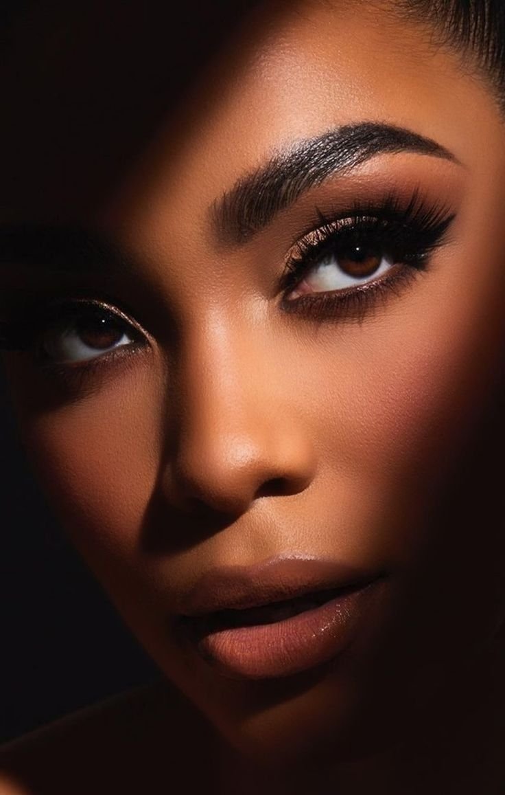 Close-up of a woman's face emphasizing her eye makeup, eyebrows, and lips with dramatic shading and highlighting.