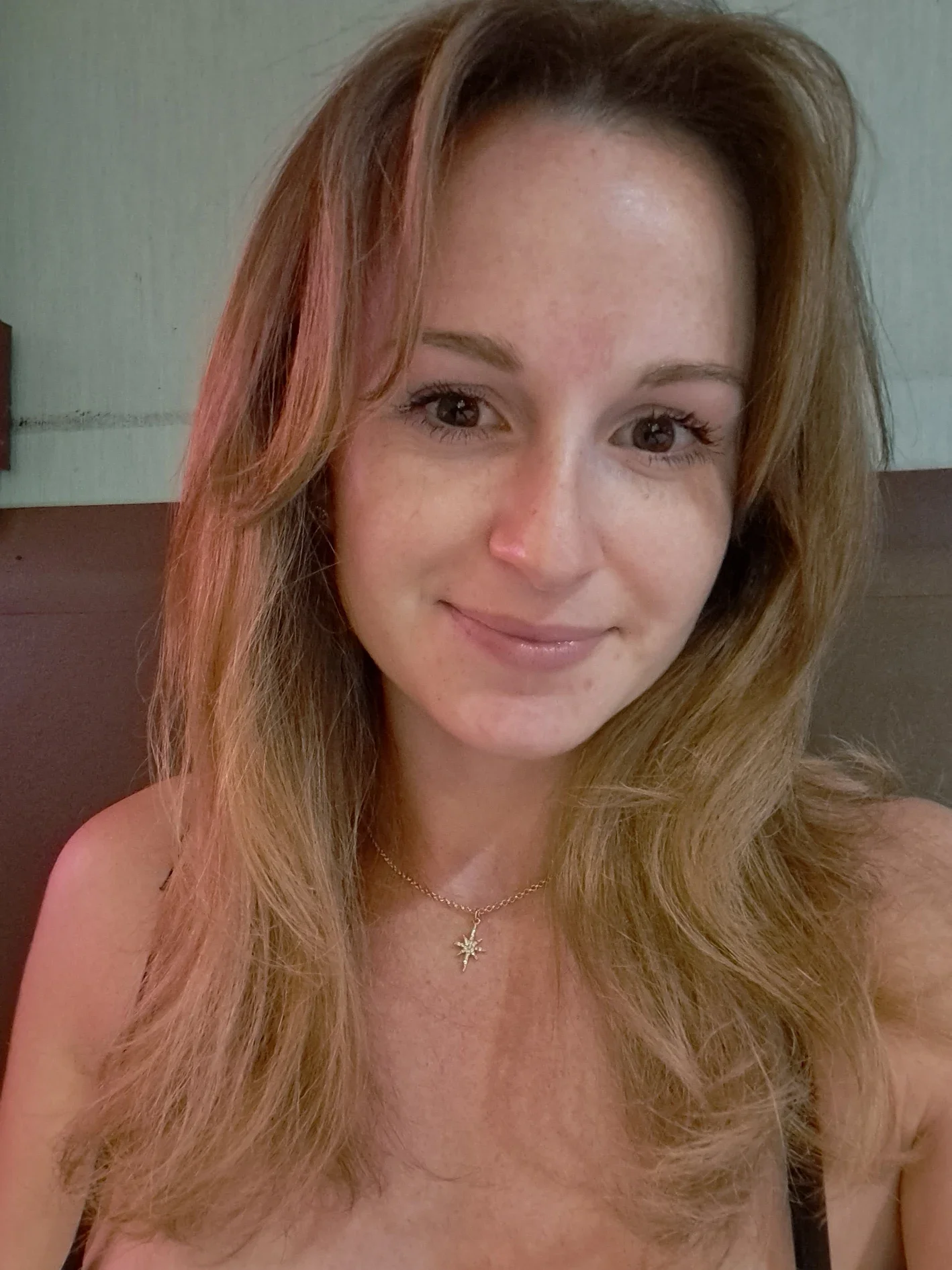 A woman with long wavy light brown hair smiling at the camera.