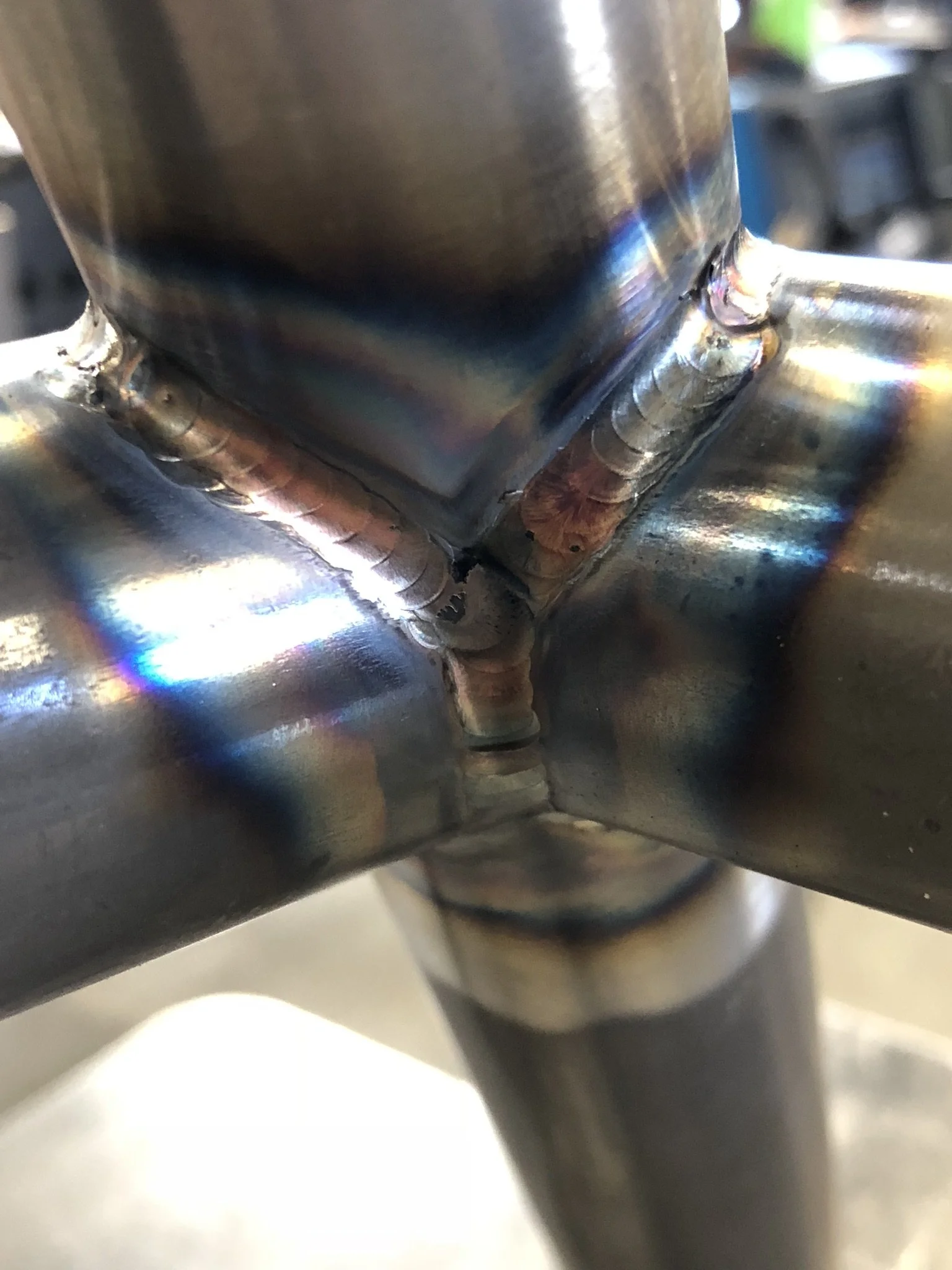 Close-up of a 4130 chromoly metal joint with welds connecting two tubes at a perpendicular angle.