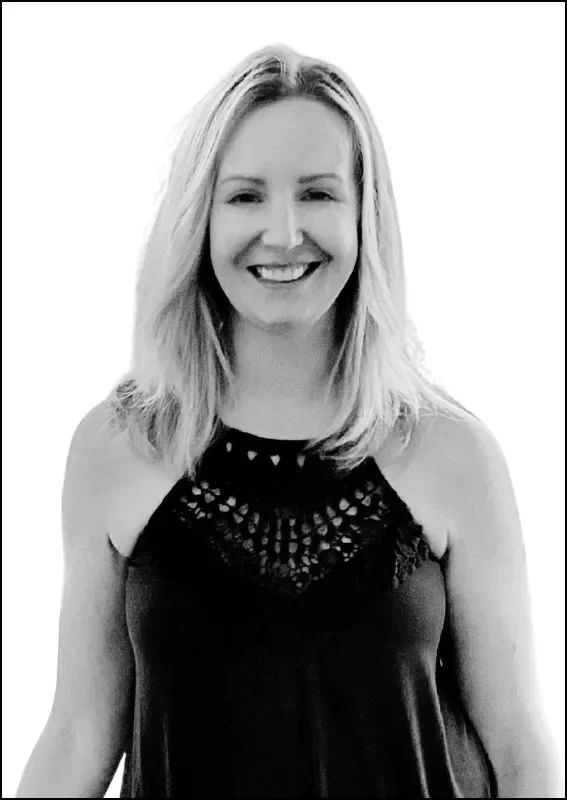 A woman with blonde hair smiling, wearing a sleeveless black dress with lace detail at the top.