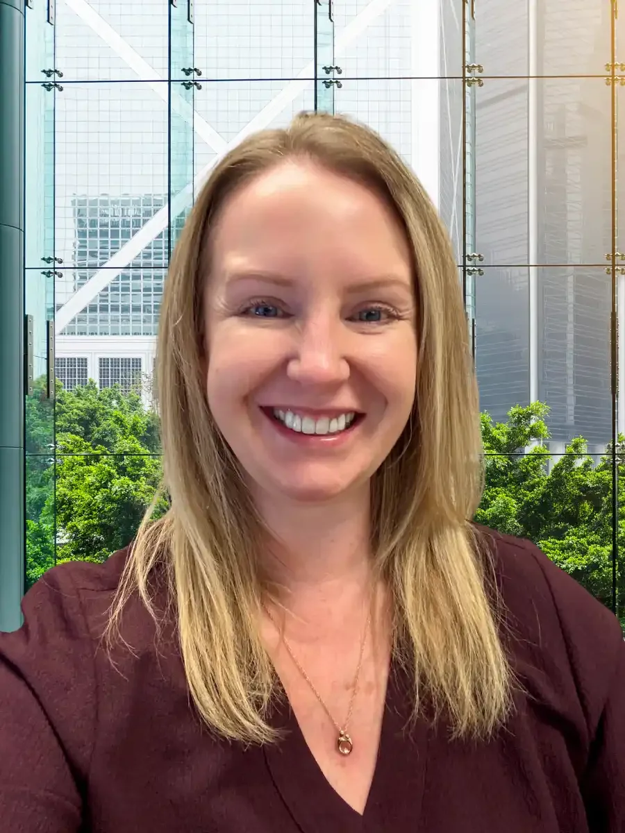 Blond woman in a red shirt smiling in a brightly lit office