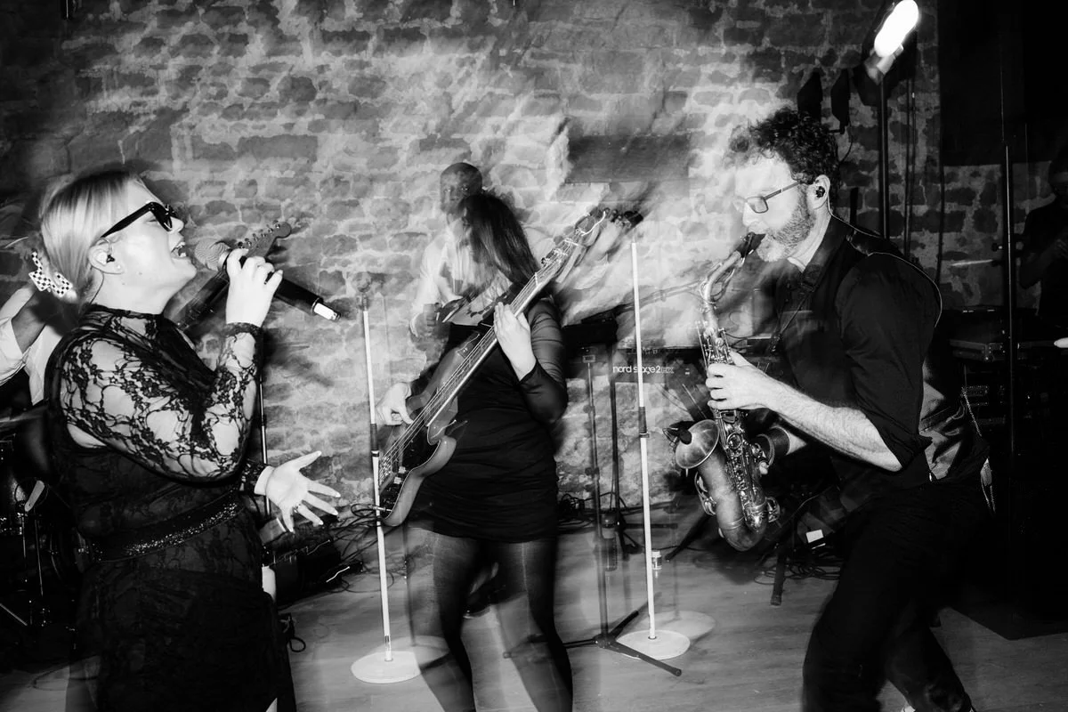 Live wedding band performing with singer and saxophonist at Tithe Barn Symondsbury Dorset during vibrant barn entertainment