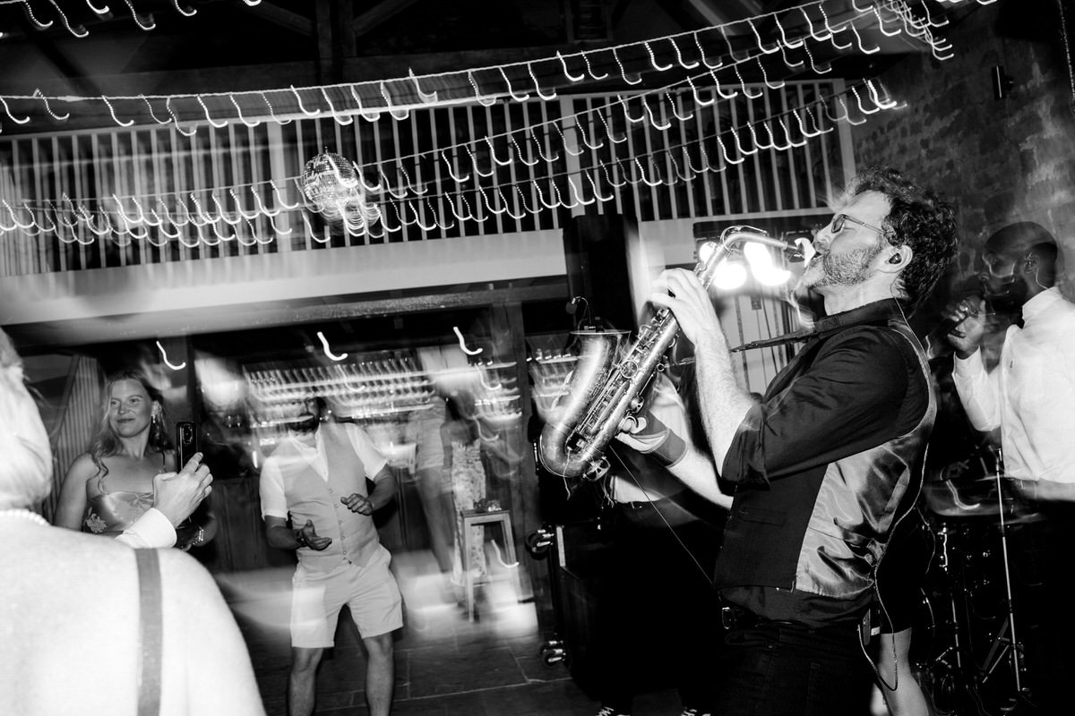 Saxophonist performing live with wedding band at Tithe Barn Symondsbury Dorset during energetic barn reception entertainment