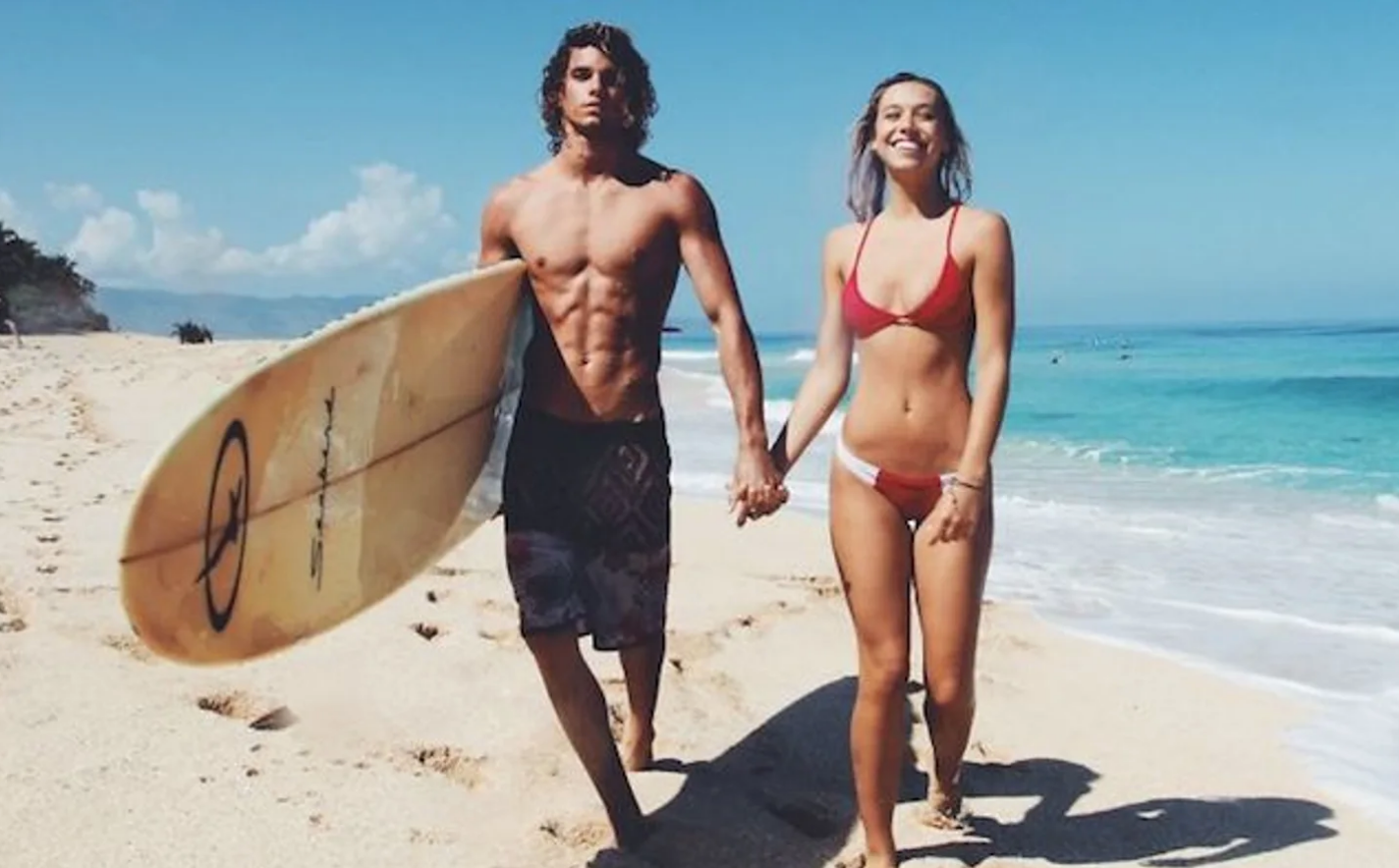 Group of people clinking champagne glasses during a celebration outdoors with blue sky and clouds in the background.