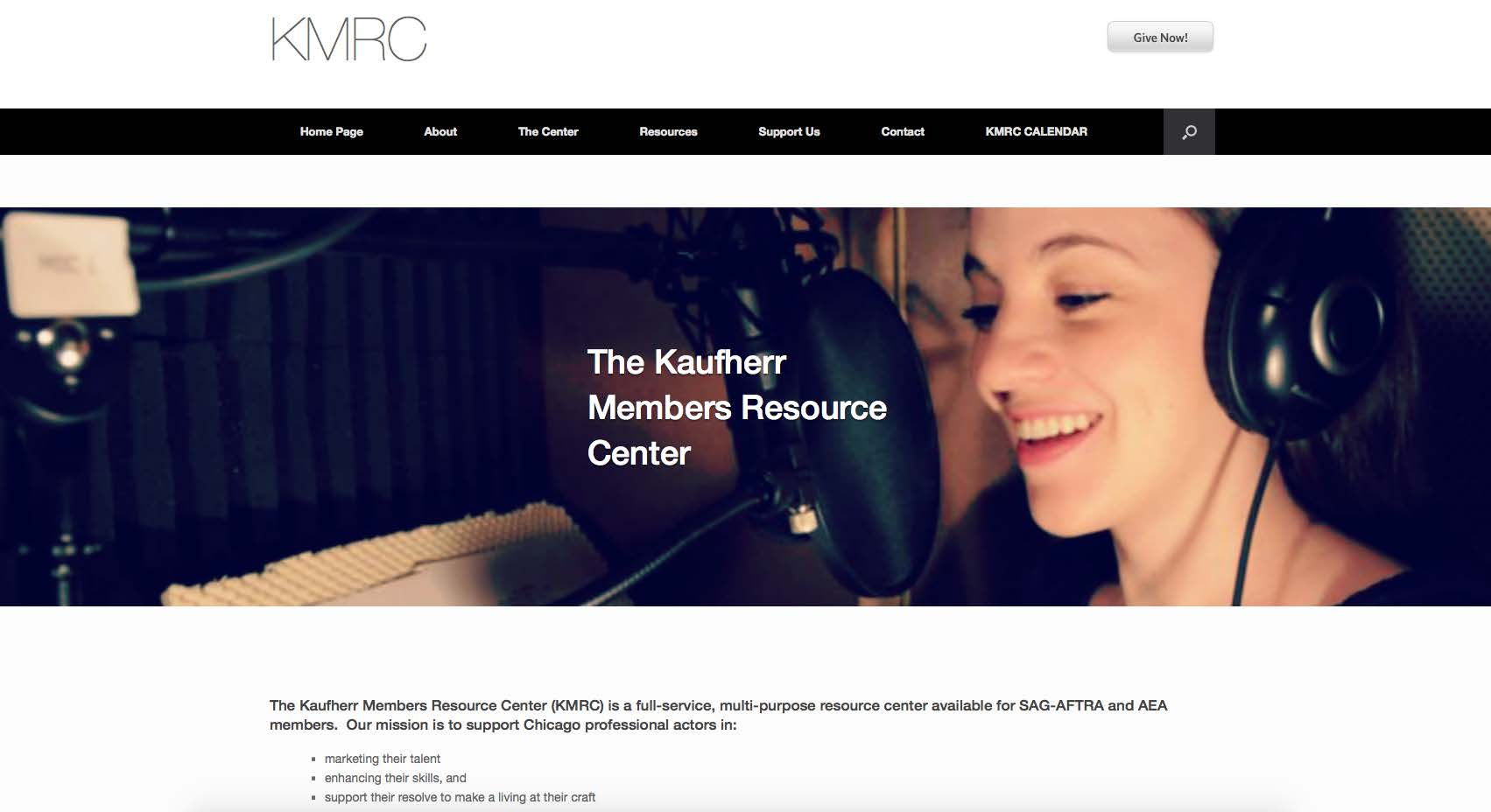 A woman in a recording studio with headphones speaking into a microphone, smiling.