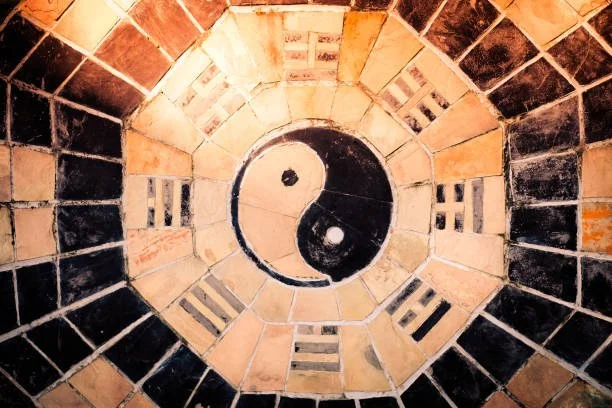 Un motif yin-yang encadré par un cercle de symboles du yin-yang, entouré de carreaux de céramique dans un design géométrique concentrique.