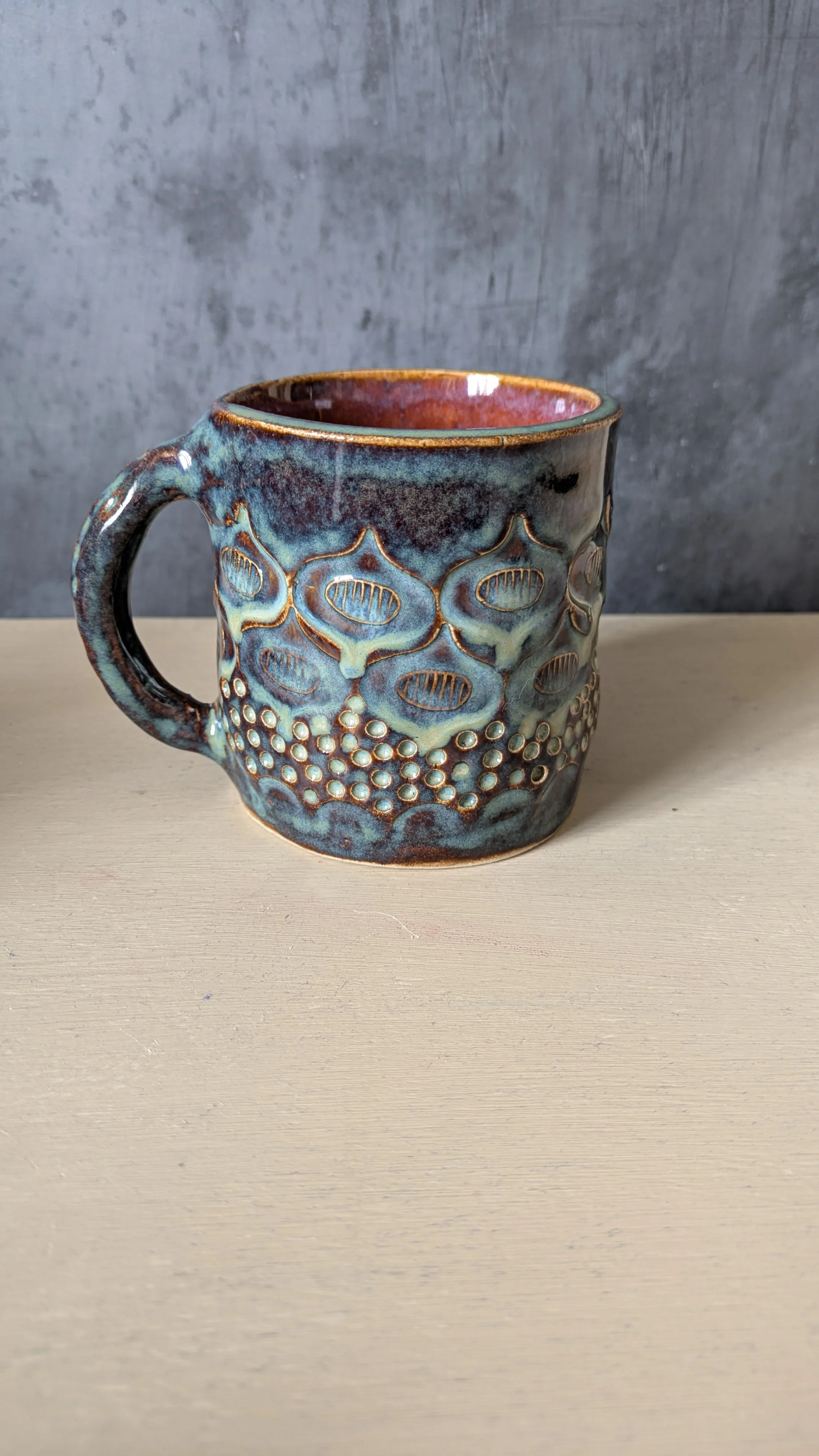 A landscape view of snow-capped mountains in the distance with rolling green and brown hills in the foreground. A modern building is situated on the hillside.