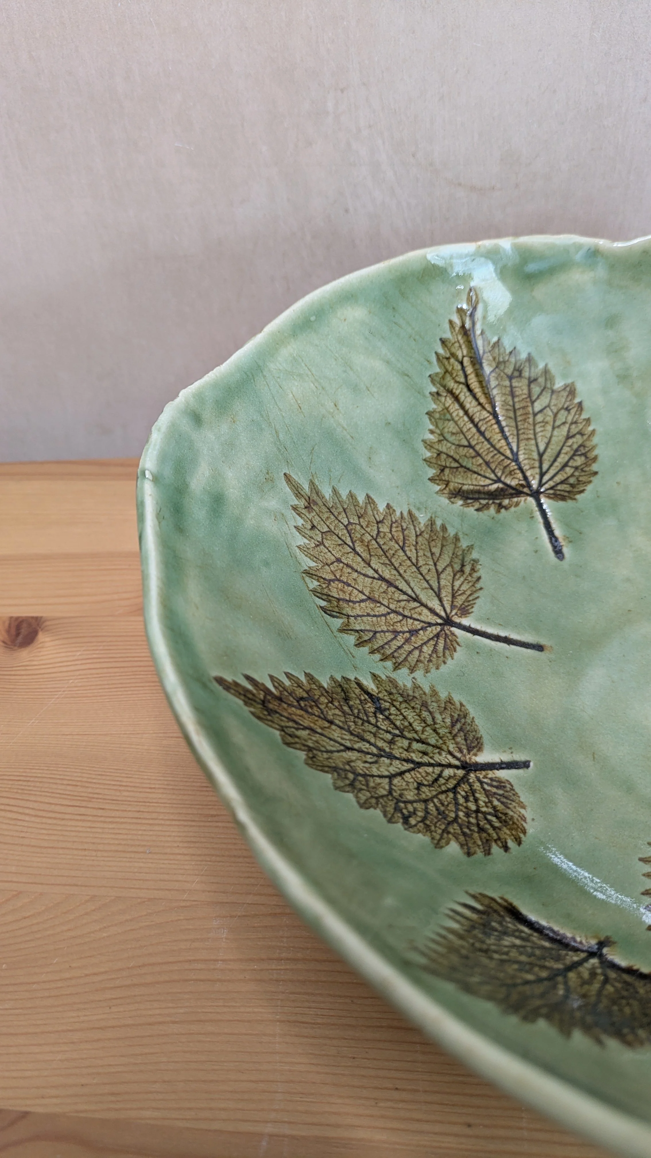Handmade ceramic bowl with green glaze and leaves in brown