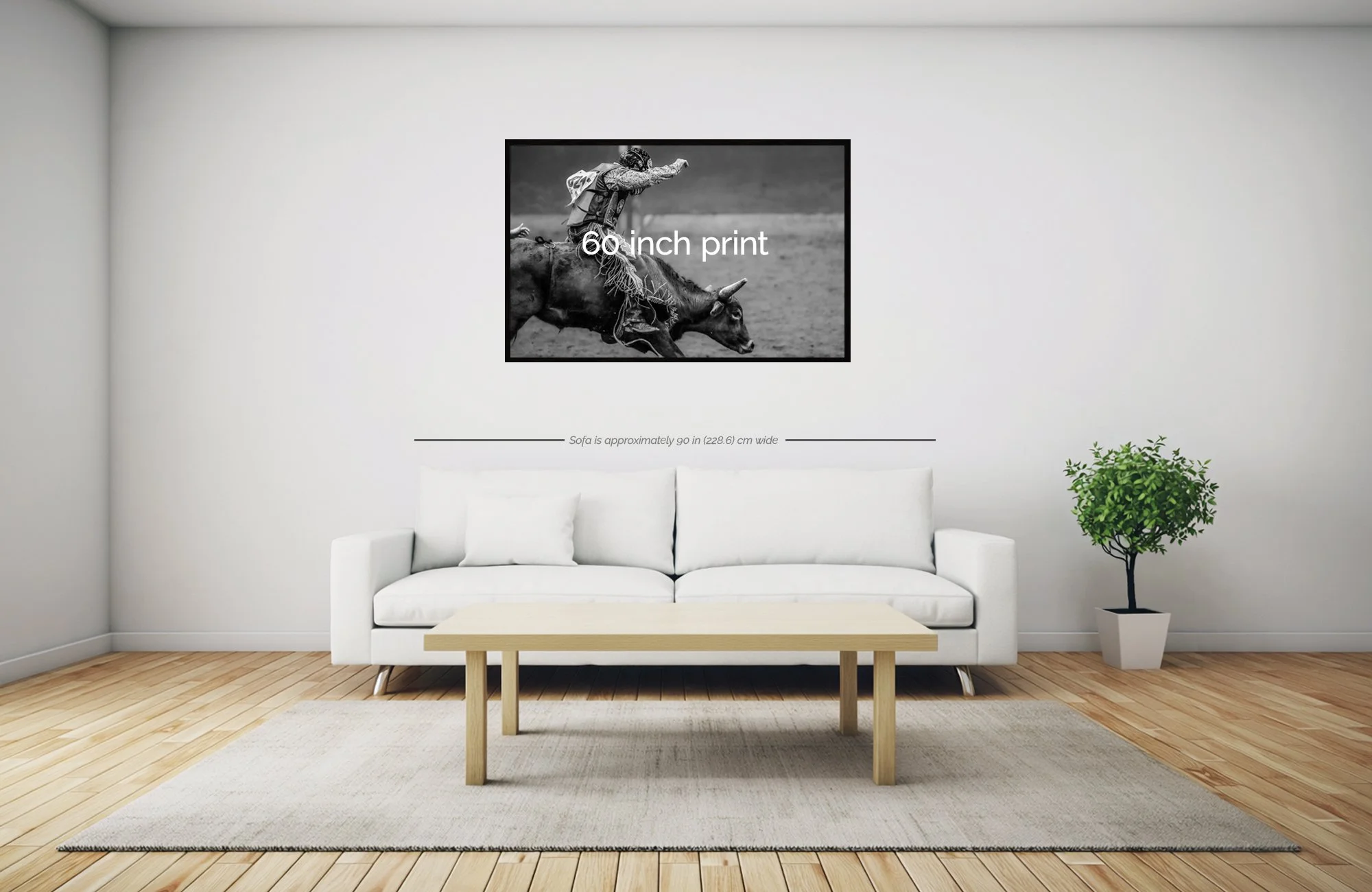 Minimalist living room with a white sofa, a small wooden coffee table, a potted plant, and wall art featuring a person riding a bull with text "60 inch print" and a note about the sofa width.