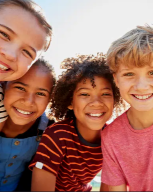 Four happy children smiling outdoors.
