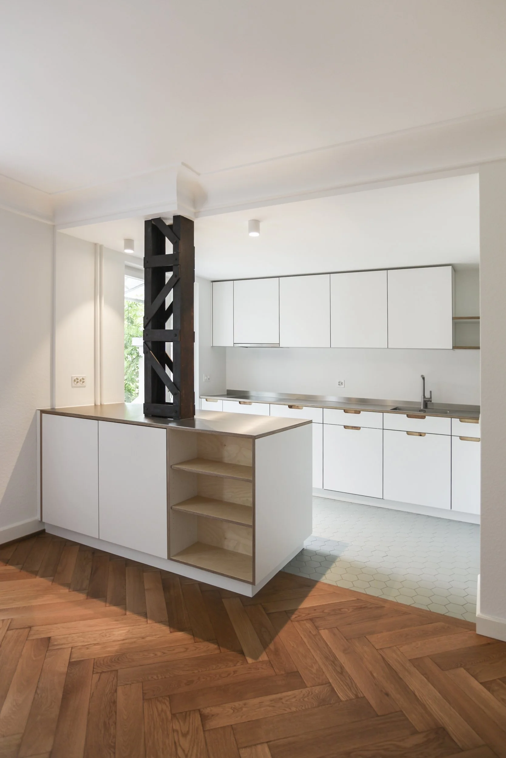 Moderne weiße Küche mit Holzakzenten, dunklem Holzstützbalken, Holzboden und hellem Fliesenboden.
