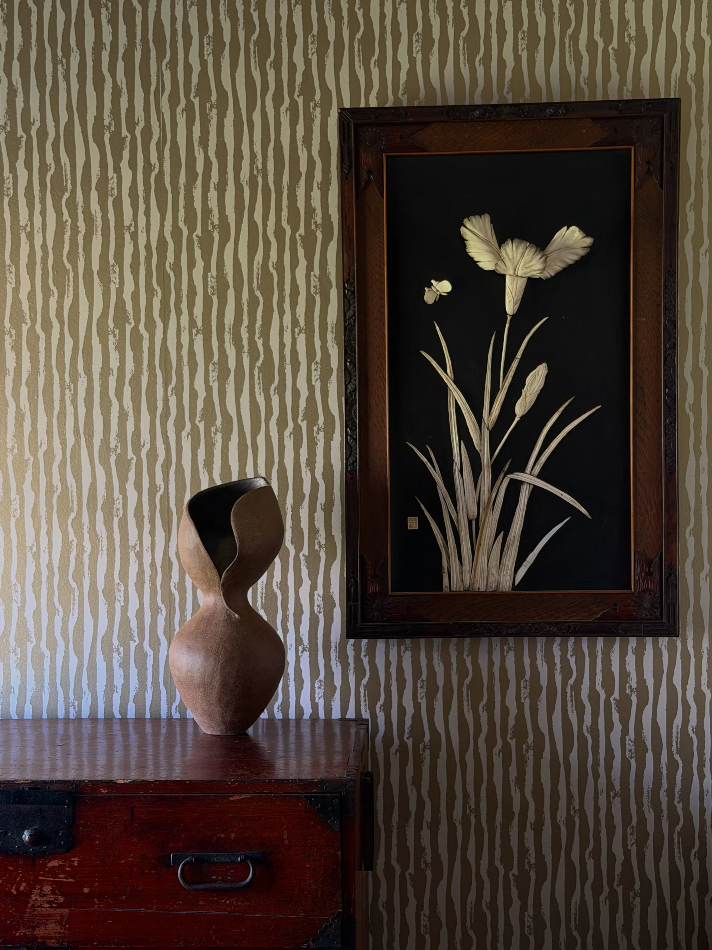 Hand-built dark stoneware vase with a twisting, figure-like silhouette suggesting a female form, styled on an antique wood chest in the Erica Tanov atelier