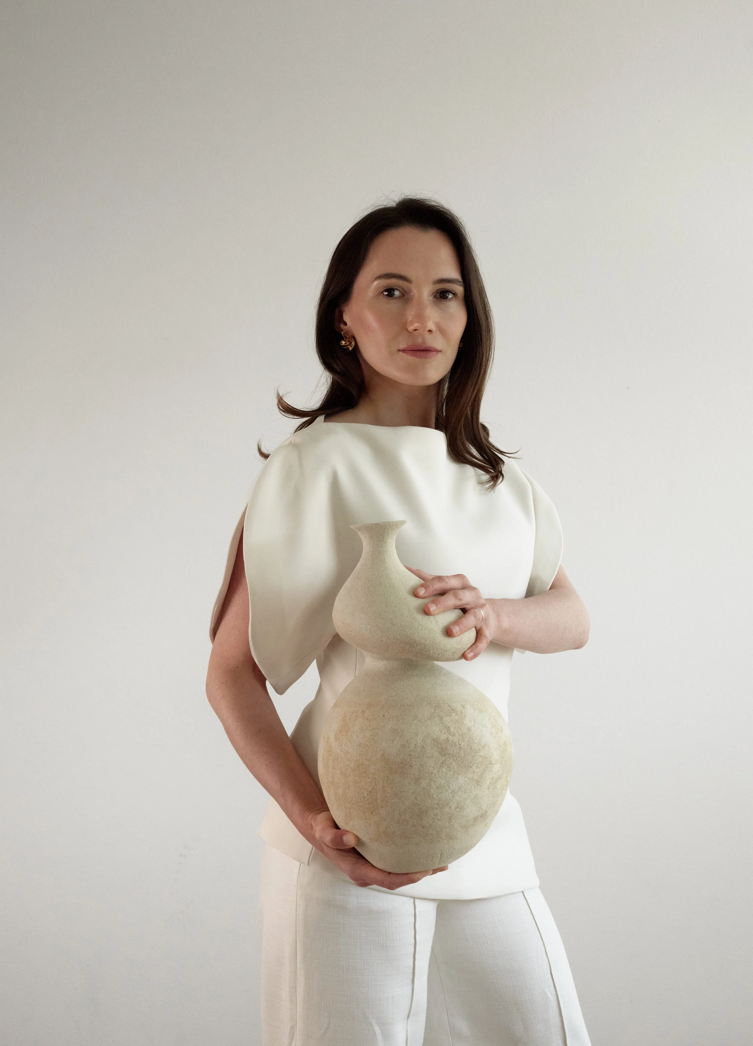 Ceramic artist Anastasia Babenko holding She, a hand-built sculptural ceramic vessel