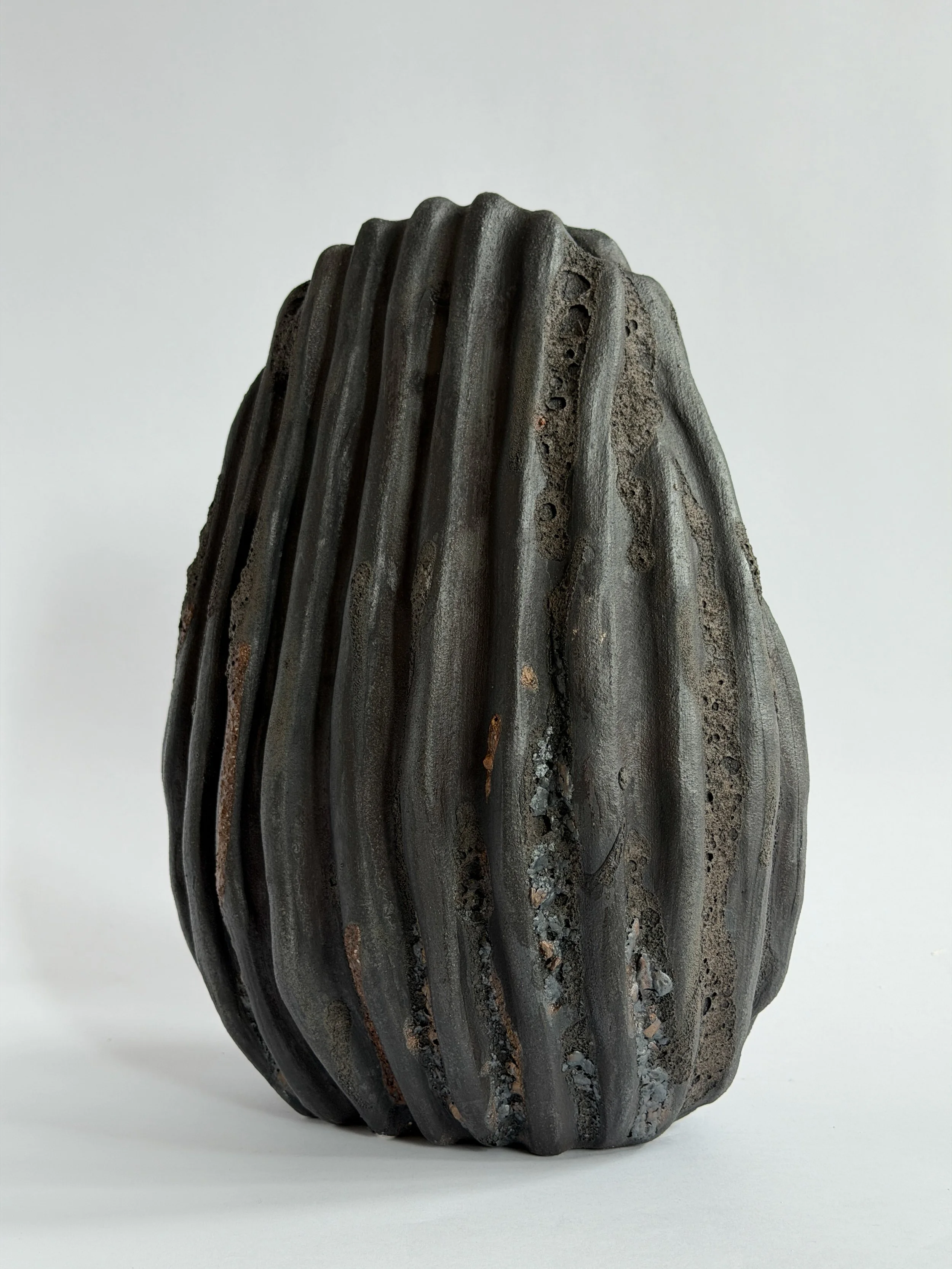 Large Black Shell Vase — hand-built ceramic vase shaped like a large deep-sea shell with heavy scalloped ridges in dark stoneware, by