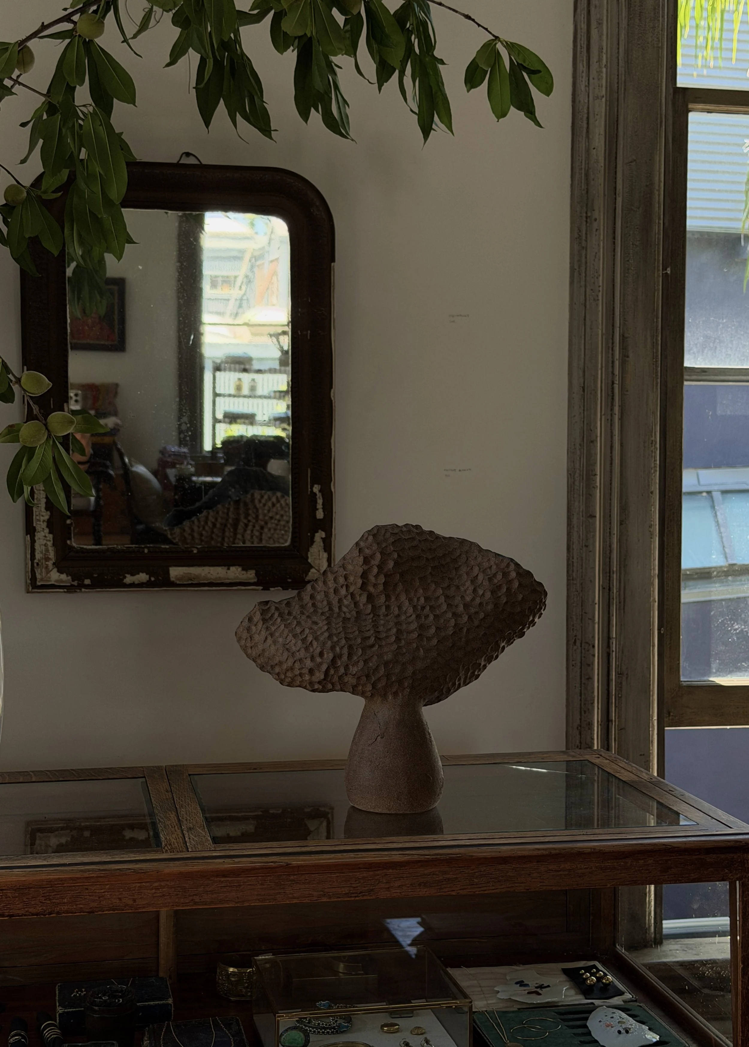 Hand-built coral-textured stoneware vase with a dimpled, hand-carved surface, on a glass case in the Erica Tanov atelier