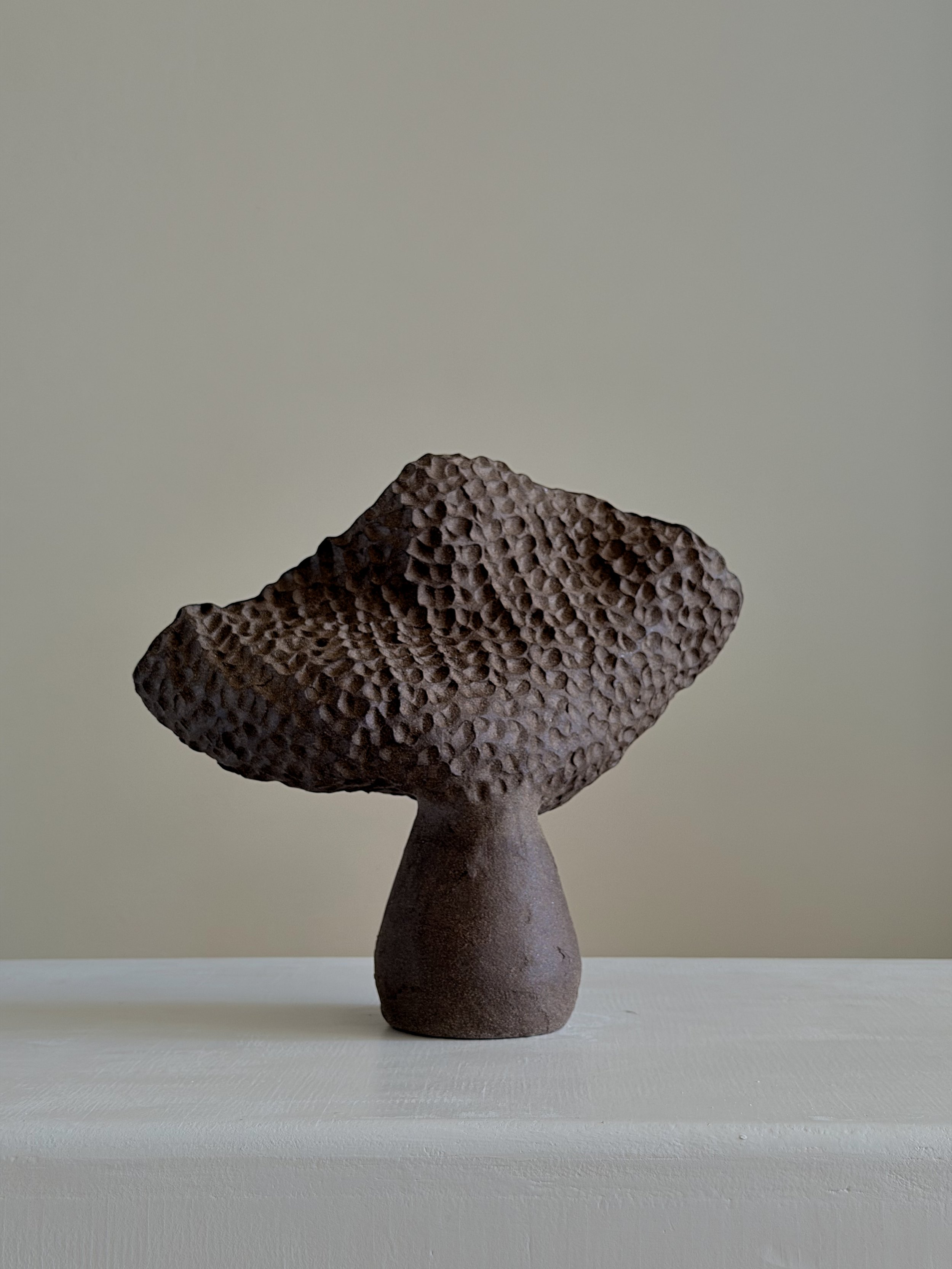 Dark brown sculptural ceramic coral vase with a honeycomb-textured fanning top on a narrow foot.