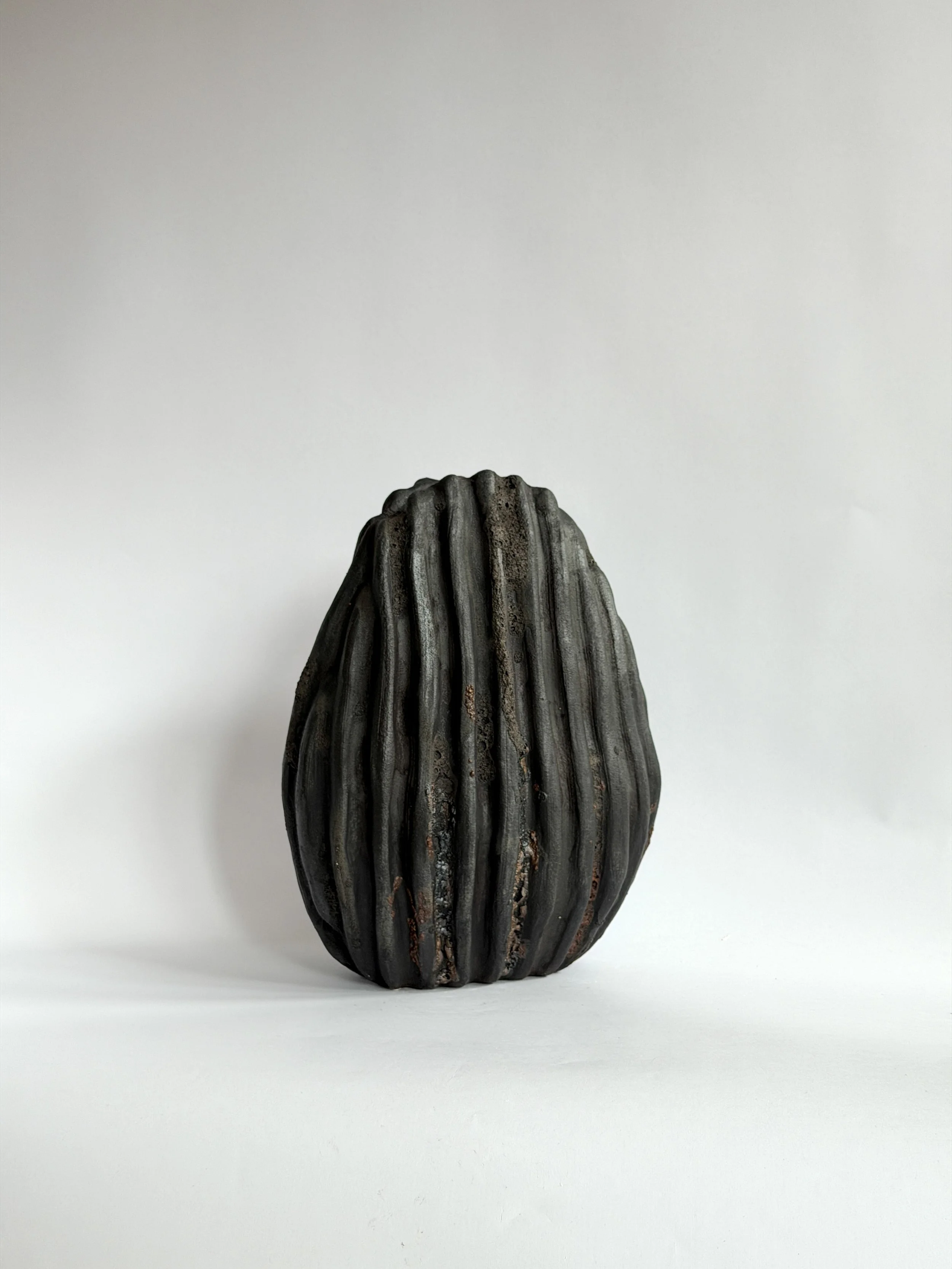 Large Black Shell Vase — hand-built ceramic vase shaped like a large deep-sea shell with heavy scalloped ridges in dark stoneware, by