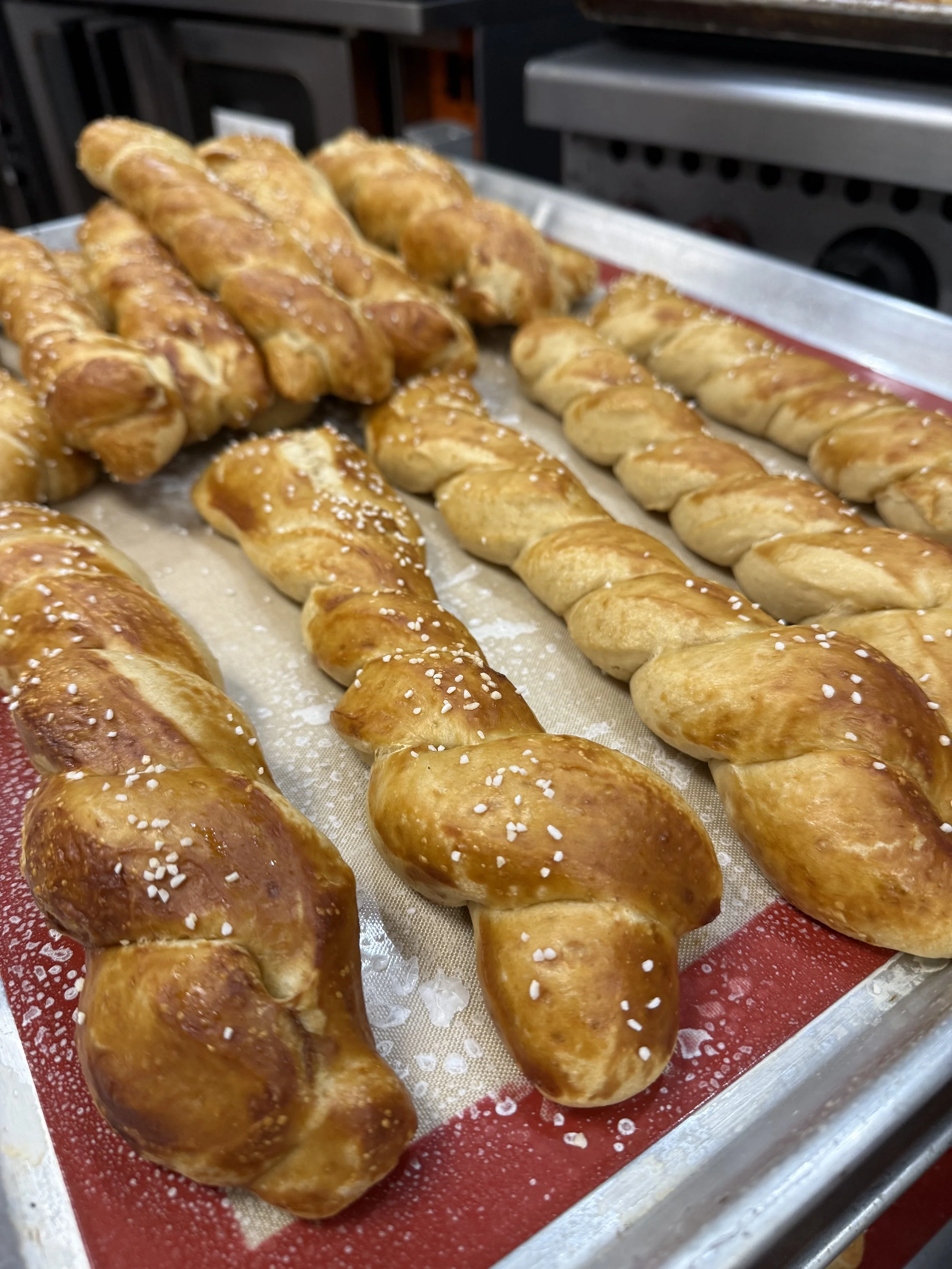 Golden-brown salted pretzel sticks on a baking tray at The Salted Bison.