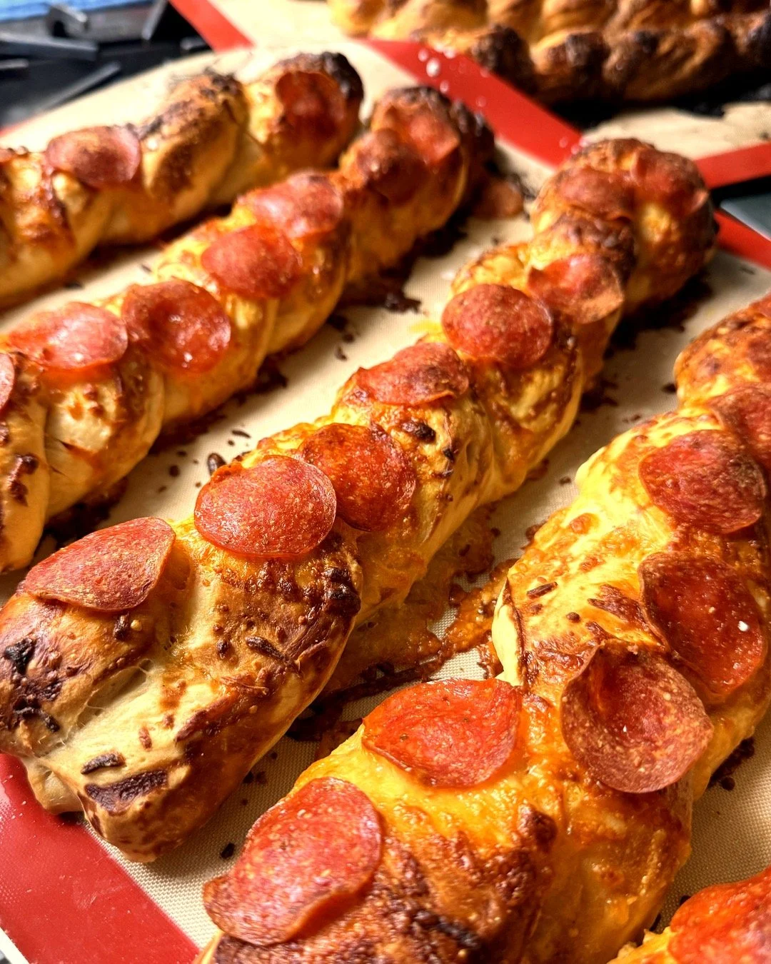 Pizza pretzel sticks topped with melted cheese and pepperoni, fresh from the oven.