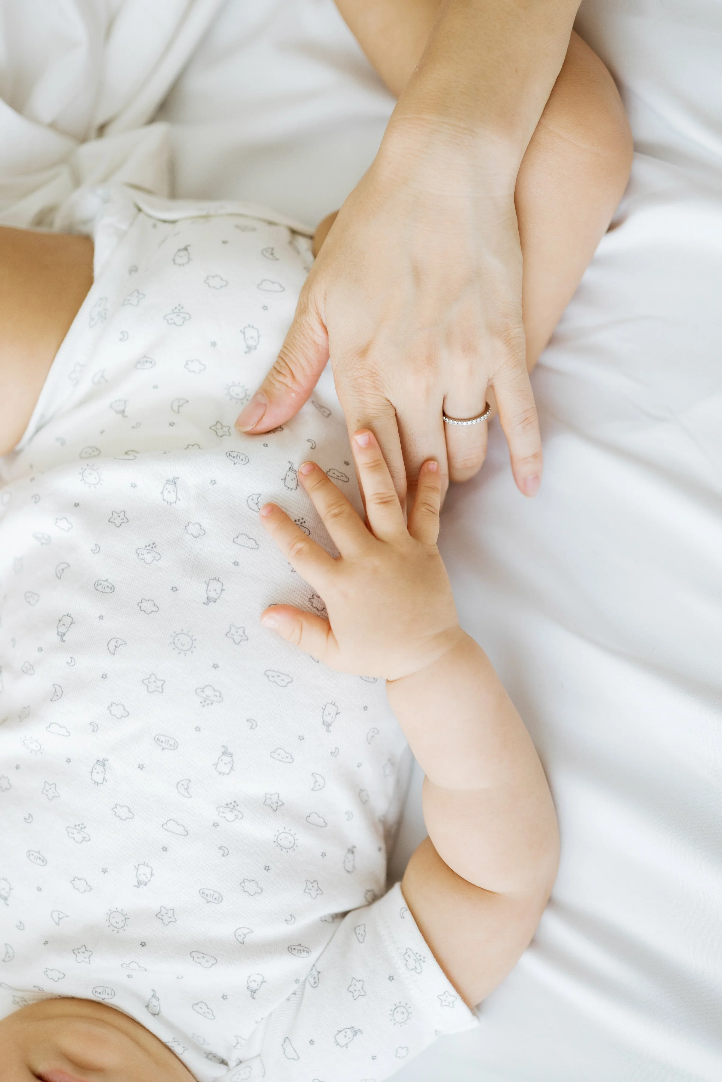 A baby and mom hold hands