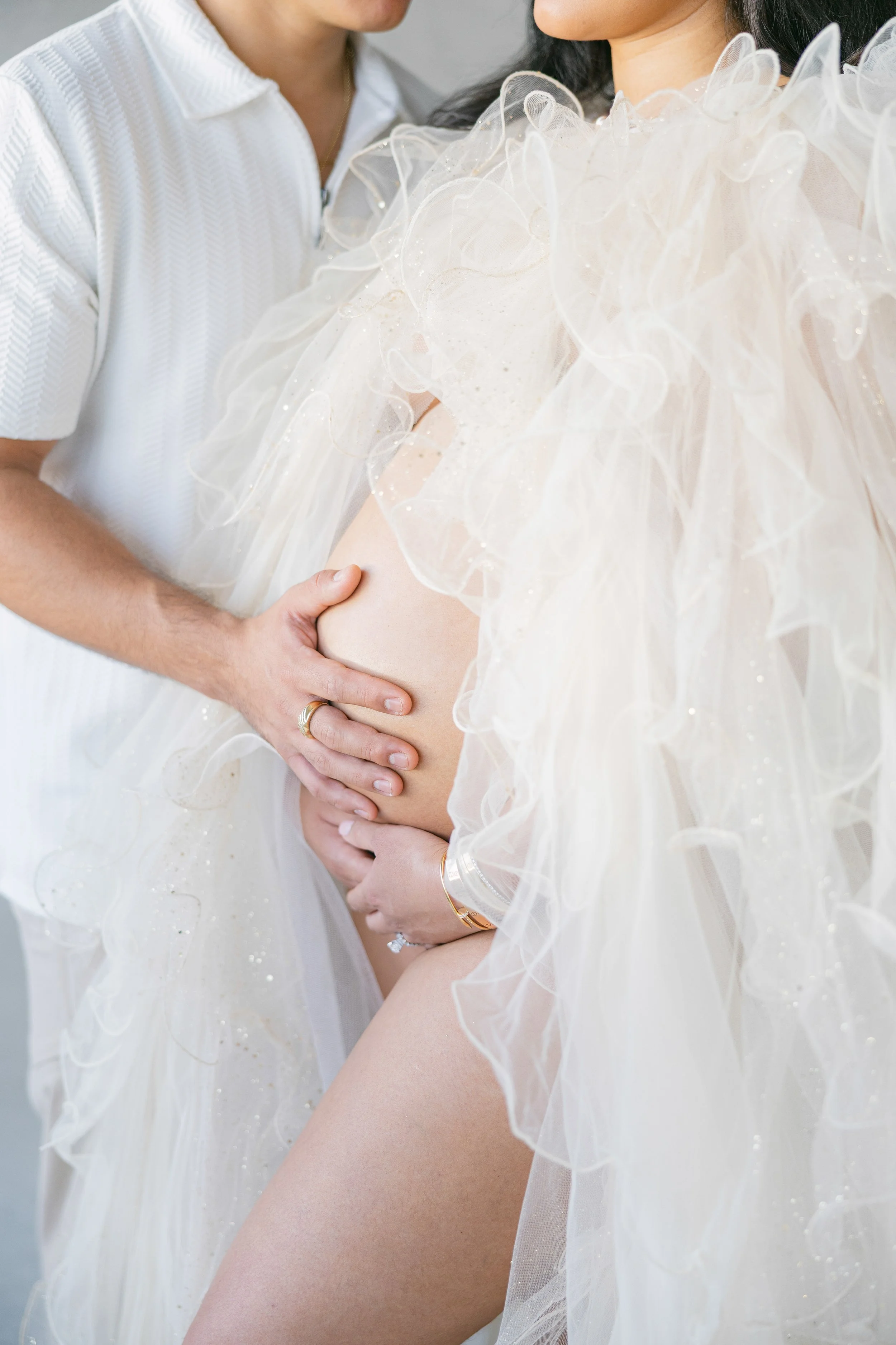 A pregnant woman with her husband's hand on her belly