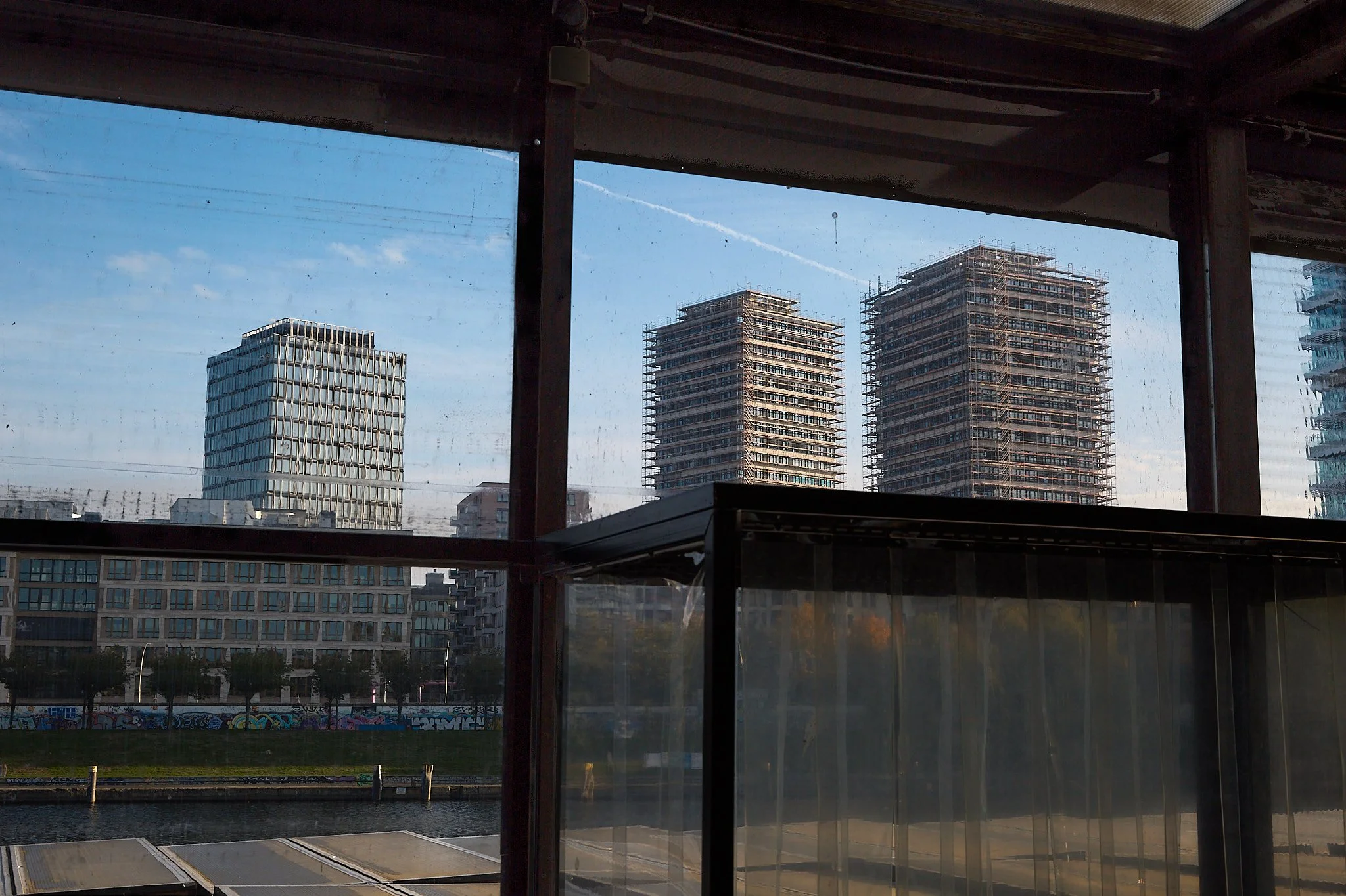 A view from the inside looking out&mdash;where architecture meets the pulse of the city. This space is a living reflection of Berlin&rsquo;s rhythm: raw, ever-evolving, and connected to its surroundings. The clean lines of modern towers in the distan