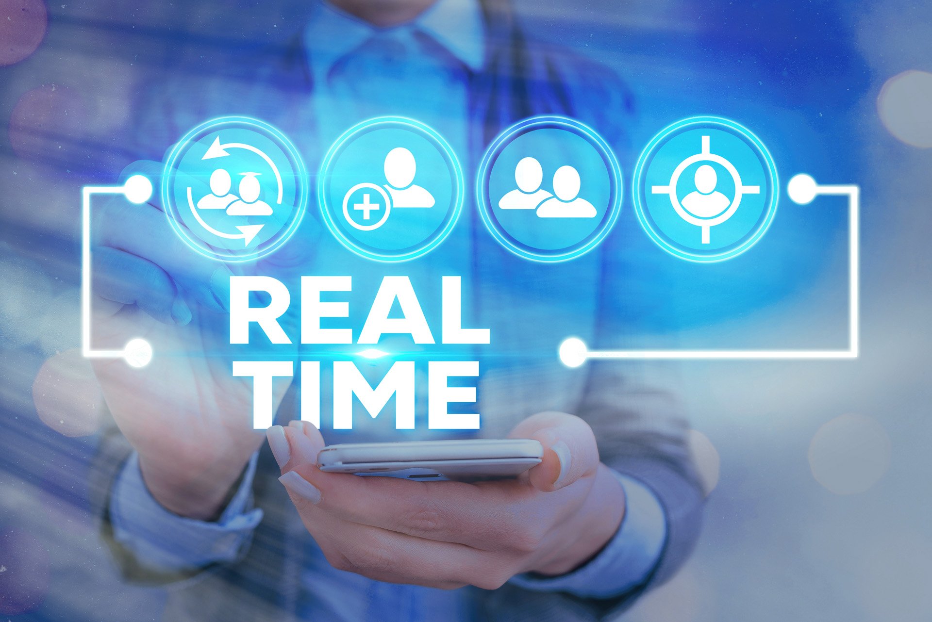 A person in a business suit holding a smartphone with a digital overlay displaying icons for user groups, addition of contacts, targeting, and the words 'REAL TIME' in blue digital graphics.