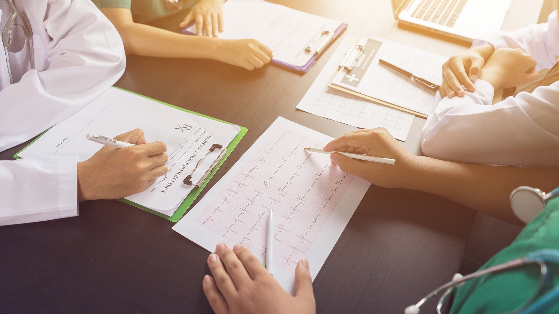 Medical professionals reviewing an electrocardiogram (ECG) report and patient medical documents during a consultation.