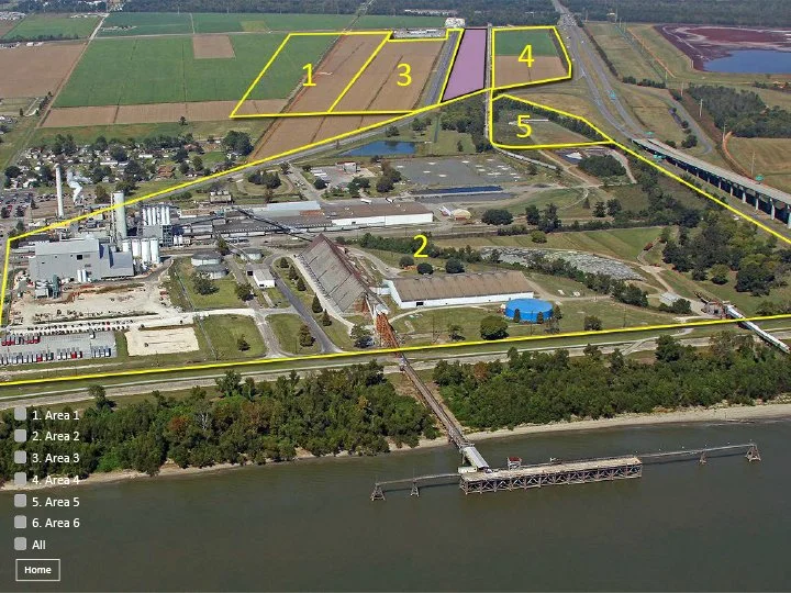 Aerial view of an industrial area with six marked areas, adjacent to a body of water and farmland, with a bridge connecting to the other side.