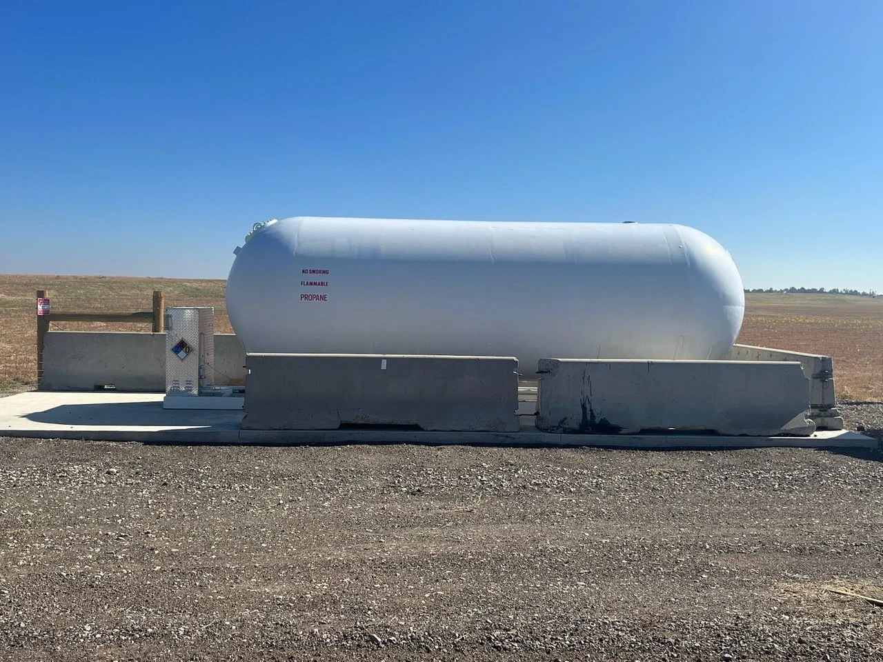 Propane station with “No Smoking” sign, safety equipment and large tank behind protective posts