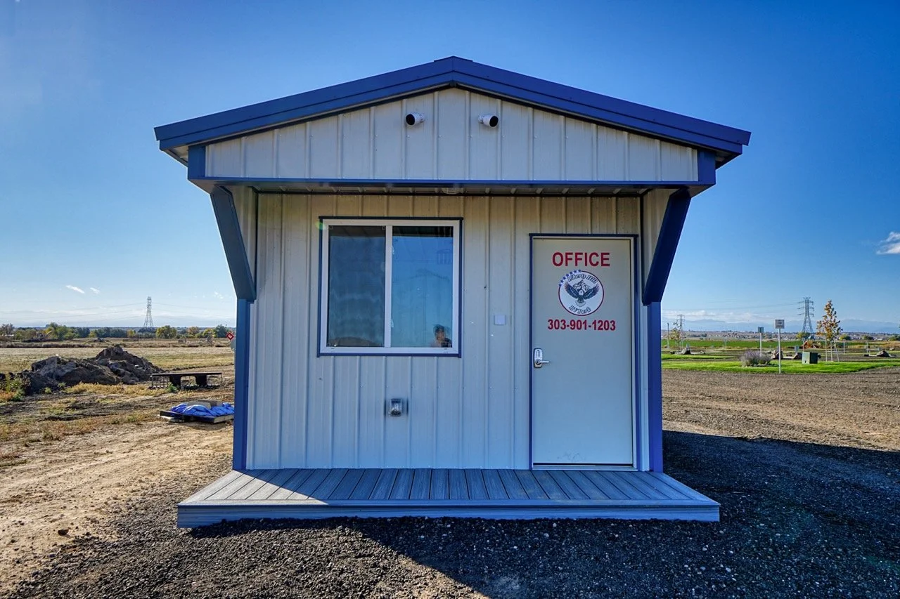 Campground office/store interior with front desk, shelves stocked with supplies, snack coolers and campground decor