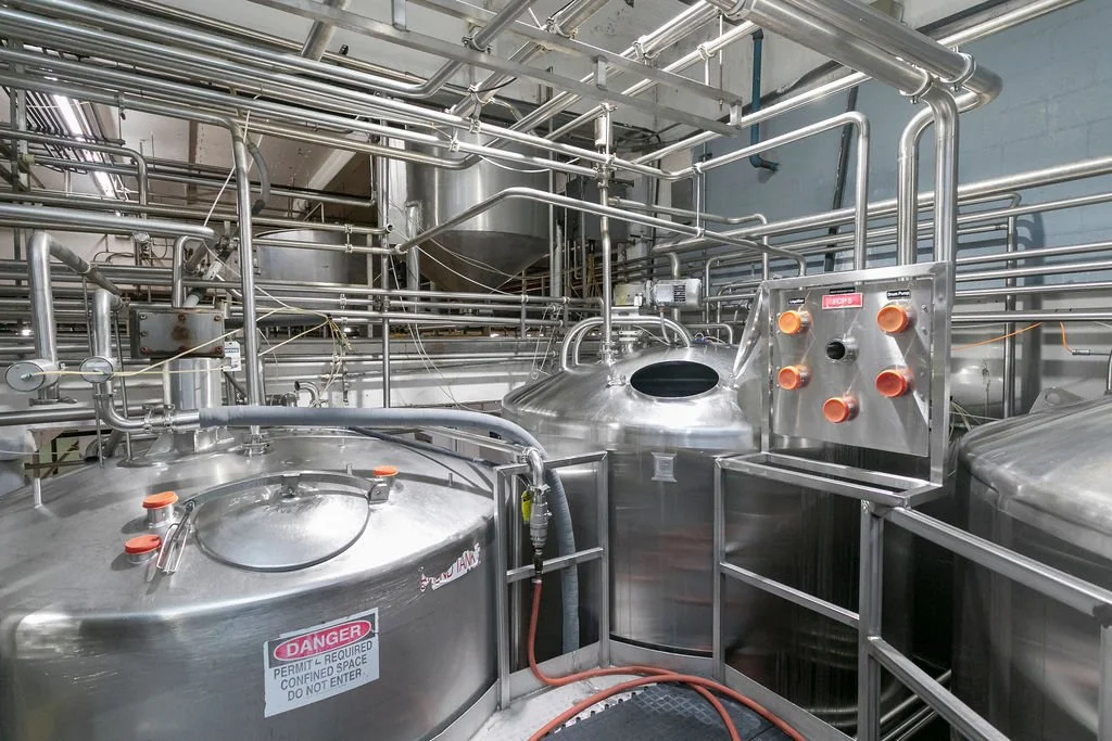 Industrial stainless steel tanks and piping systems in a manufacturing plant.