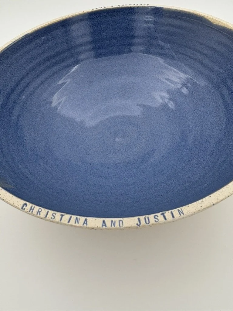 A blue ceramic bowl with a white rim and the words "CHRISTINA AND JUSTIN" inscribed around the edge.