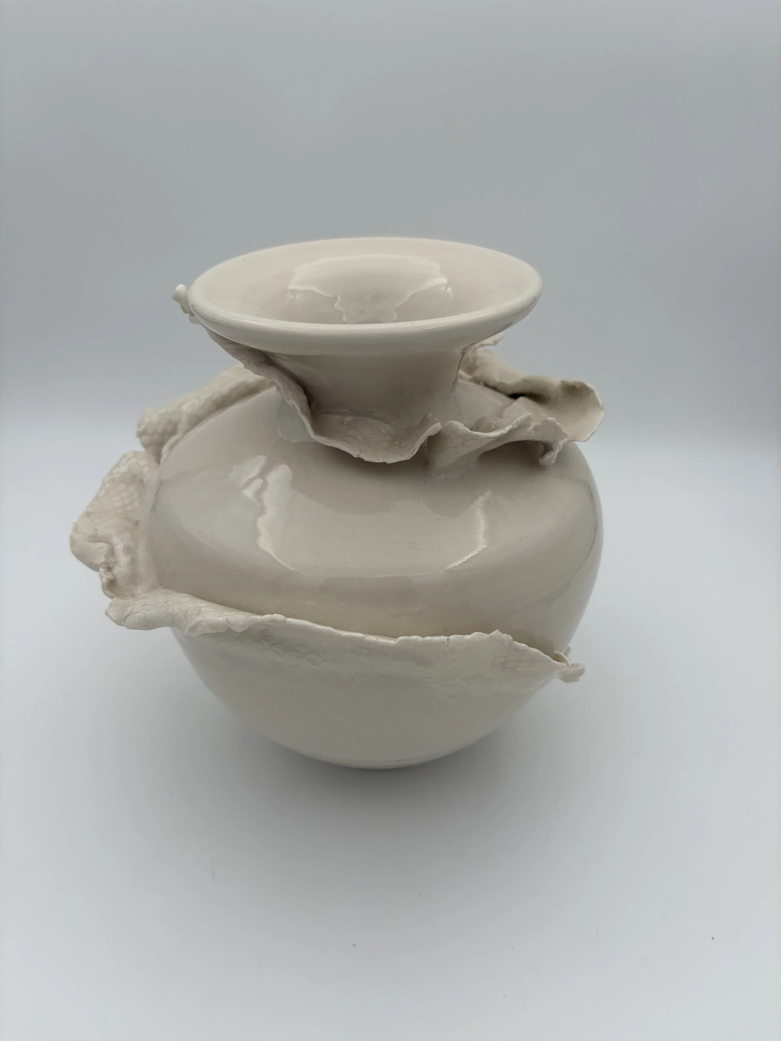 Off-white ceramic vase with layered, uneven, textured rims and two small bowls stacked on top, set against a plain white background.