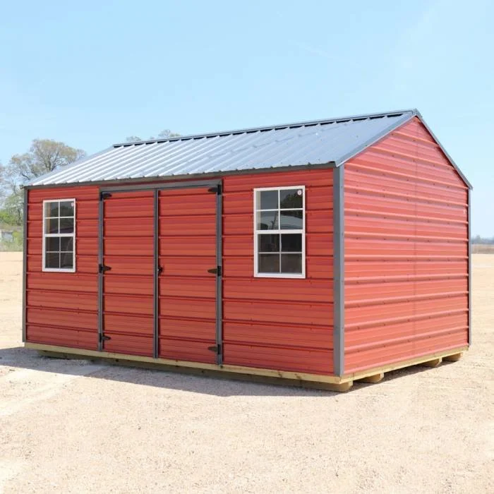 Red metal shed with two windows and double doors, sitting on a wooden base outside under a blue sky.