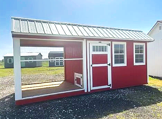Small red and white chicken coop with a metallic roof and open front porch.