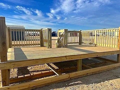 New wooden deck under construction with supporting beams and railings in an outdoor area under a cloudy sky.