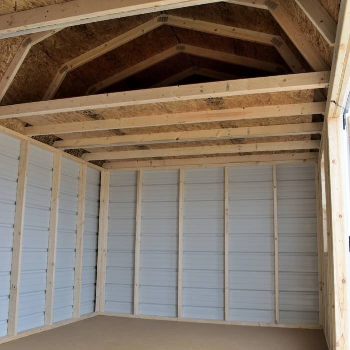 Interior of a wooden garage with unfinished walls and ceiling framing, showing exposed beams and support studs.